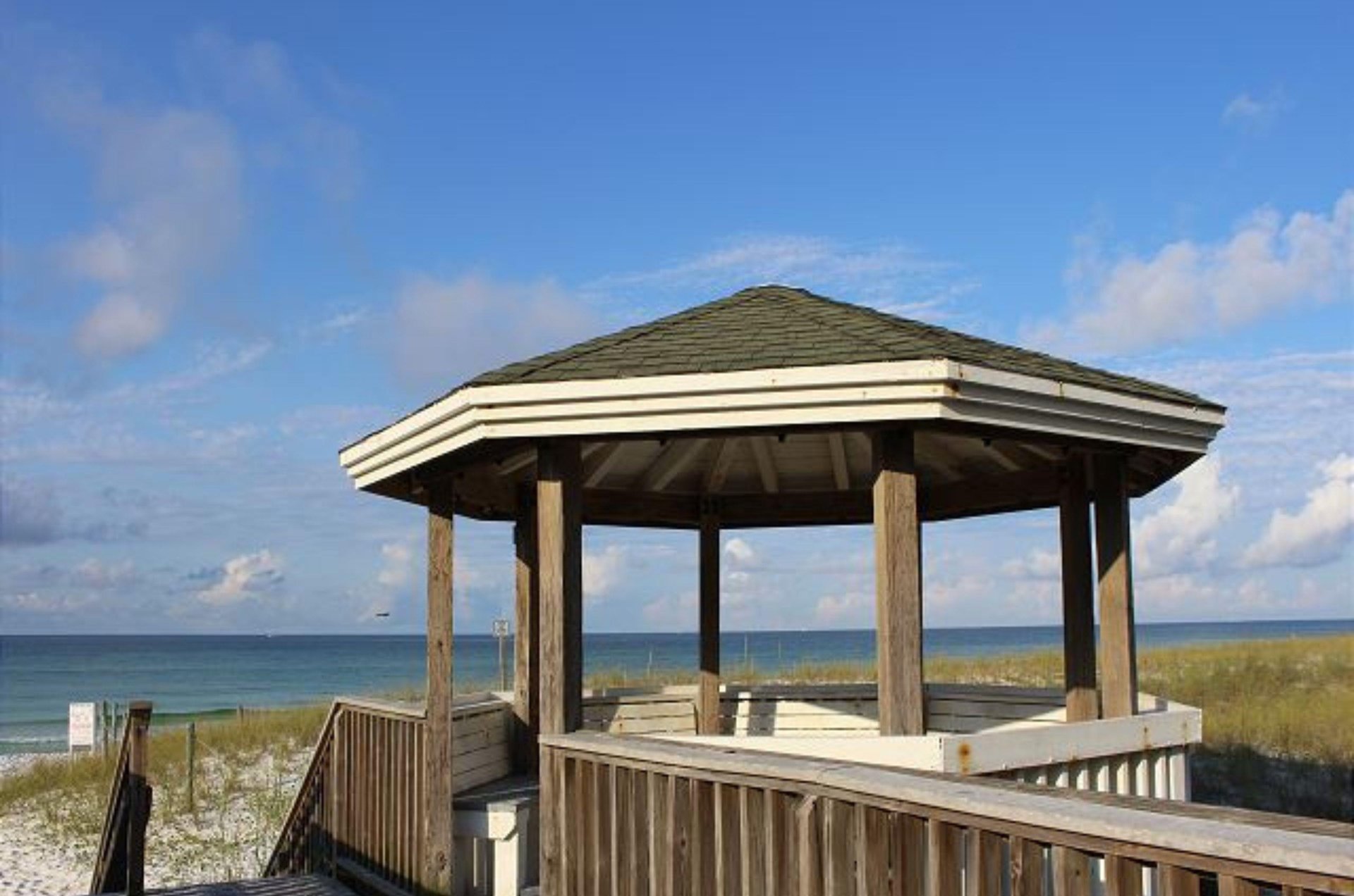 A beachside gazebo with covered seating and sweeping Gulf views