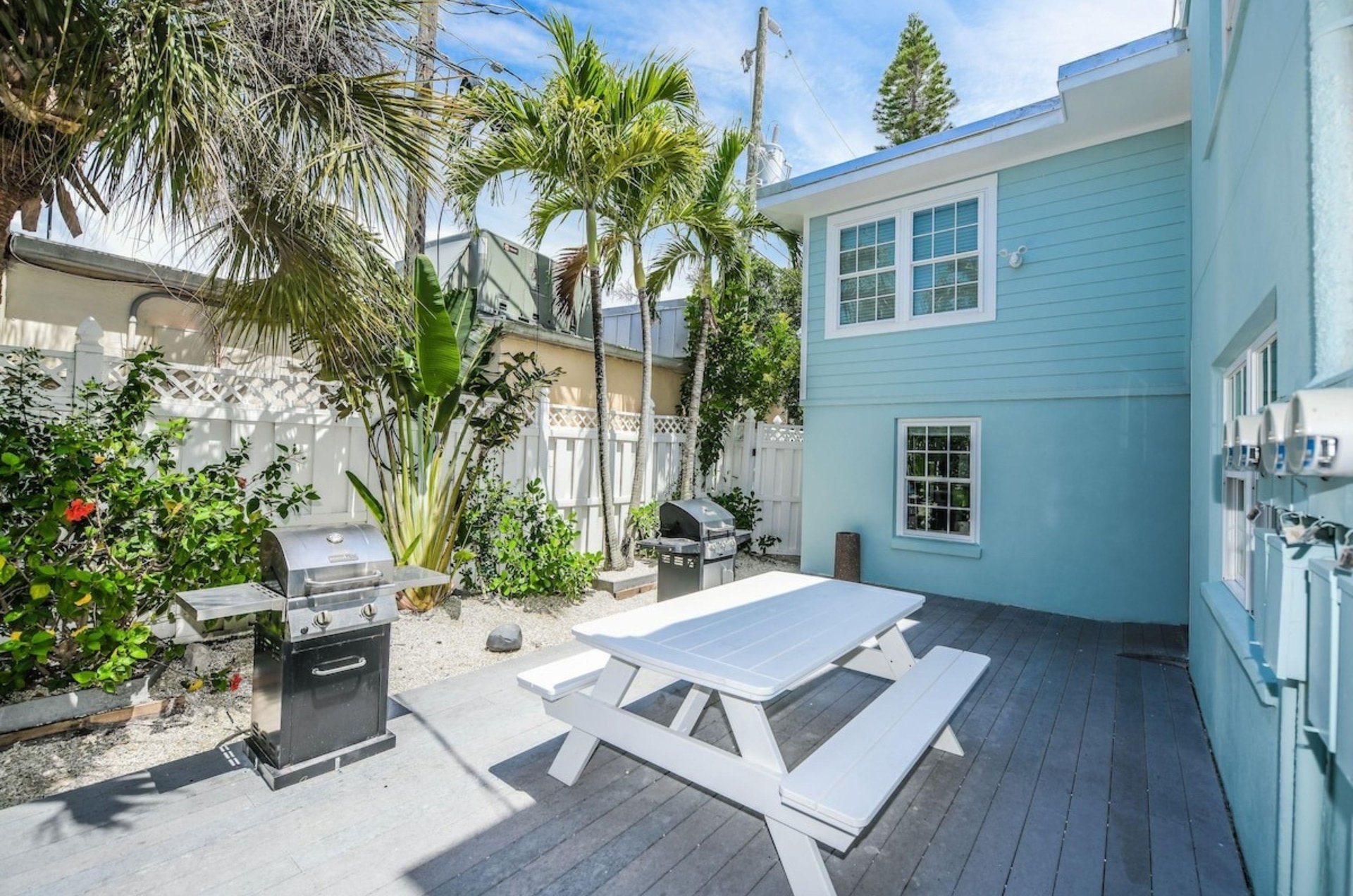 A white picnic table and a barbecue grill on an outdoor patio at Tropical Breeze Resort