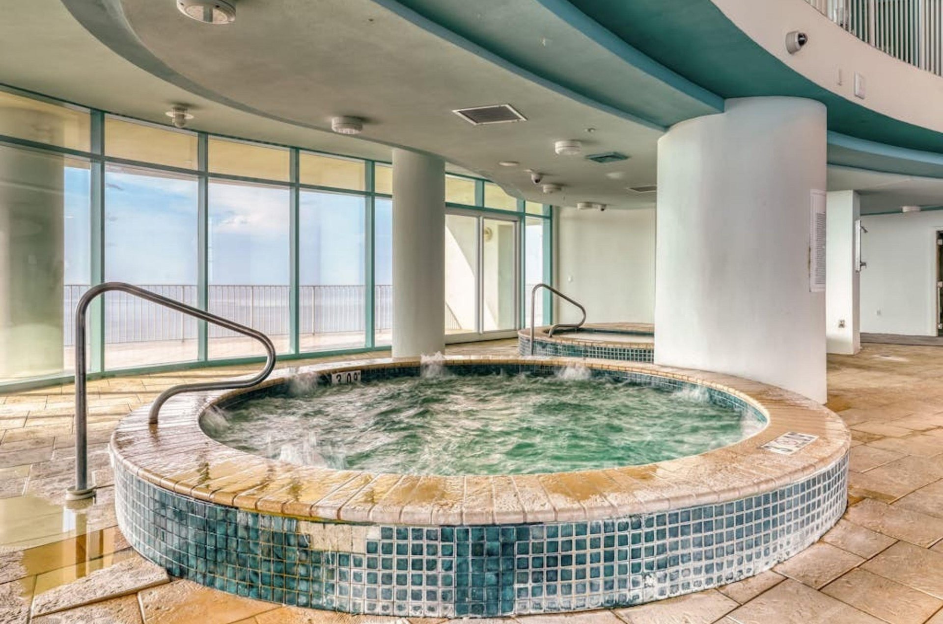 The indoor community hot tub next to floor to ceiling windows at Turquoise Place