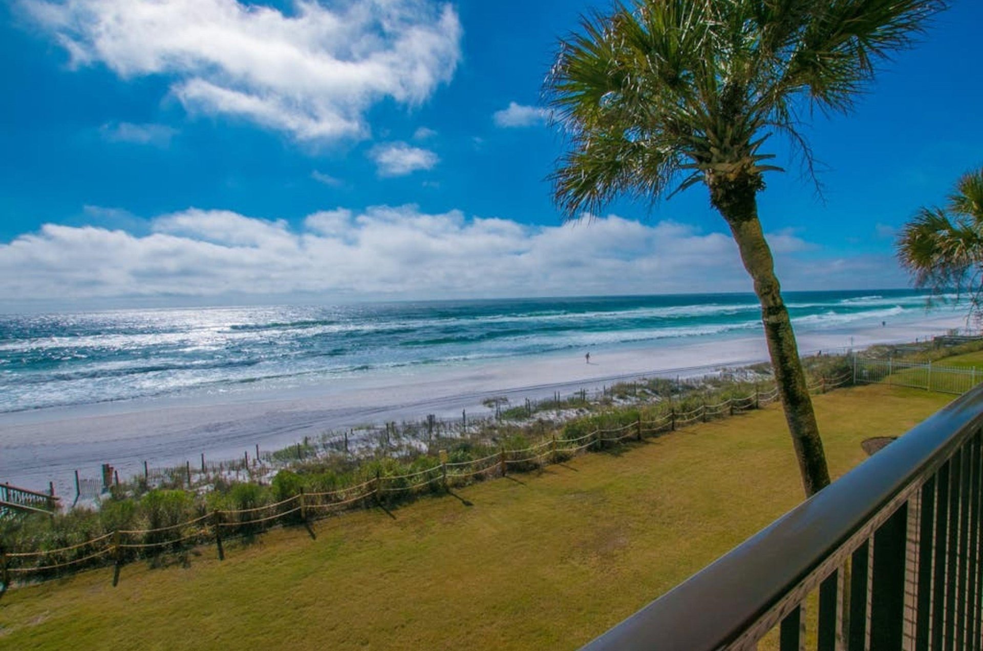 View from a balcony of lush green grass next to the beach and the Gulf