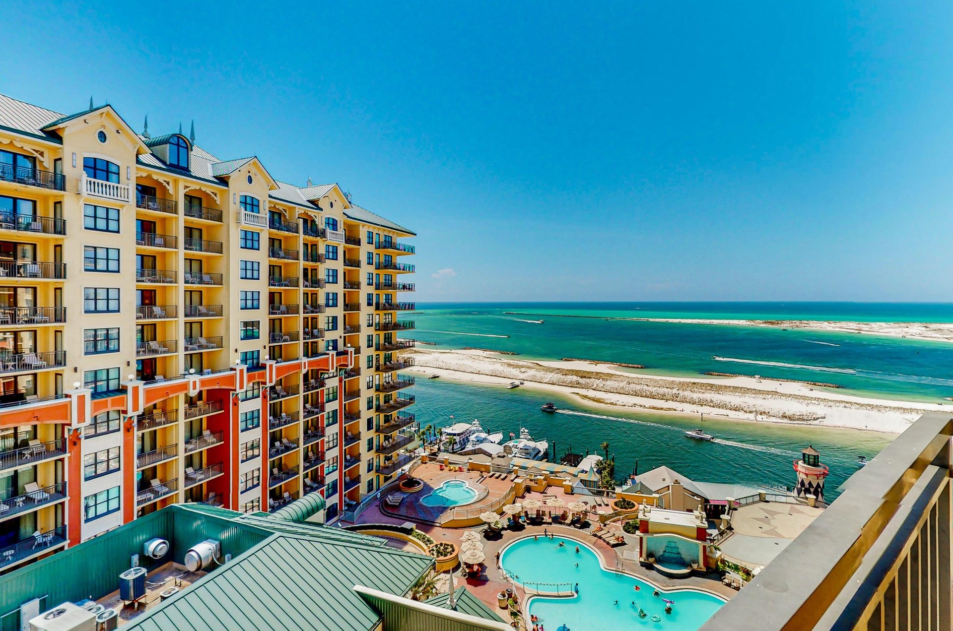 Emerald Grande balconies overlooking the pool area, Destin Harbor, Destin Pass, and the Gulf.