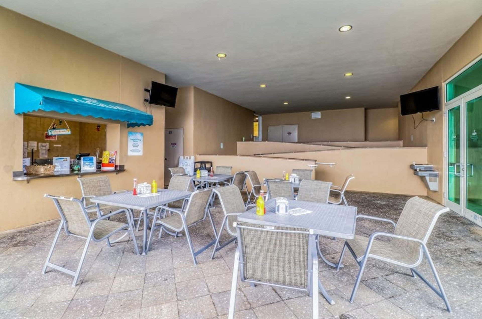 Dining chairs and tables next to the order window at the poolside cafe