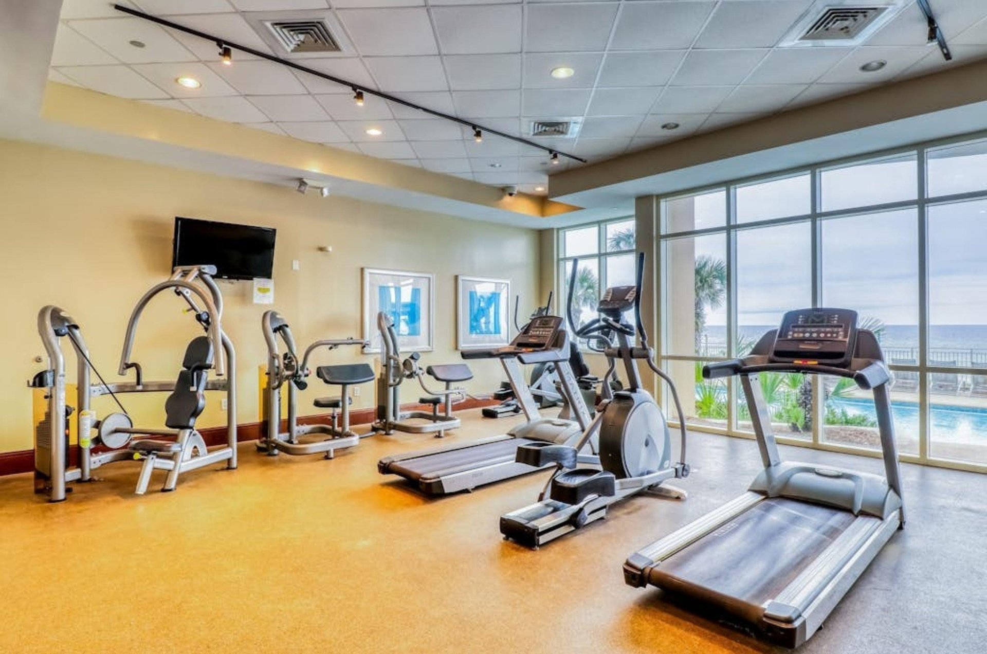 Strength and cardio equipment next to windows in the fitness center at Aqua Resort