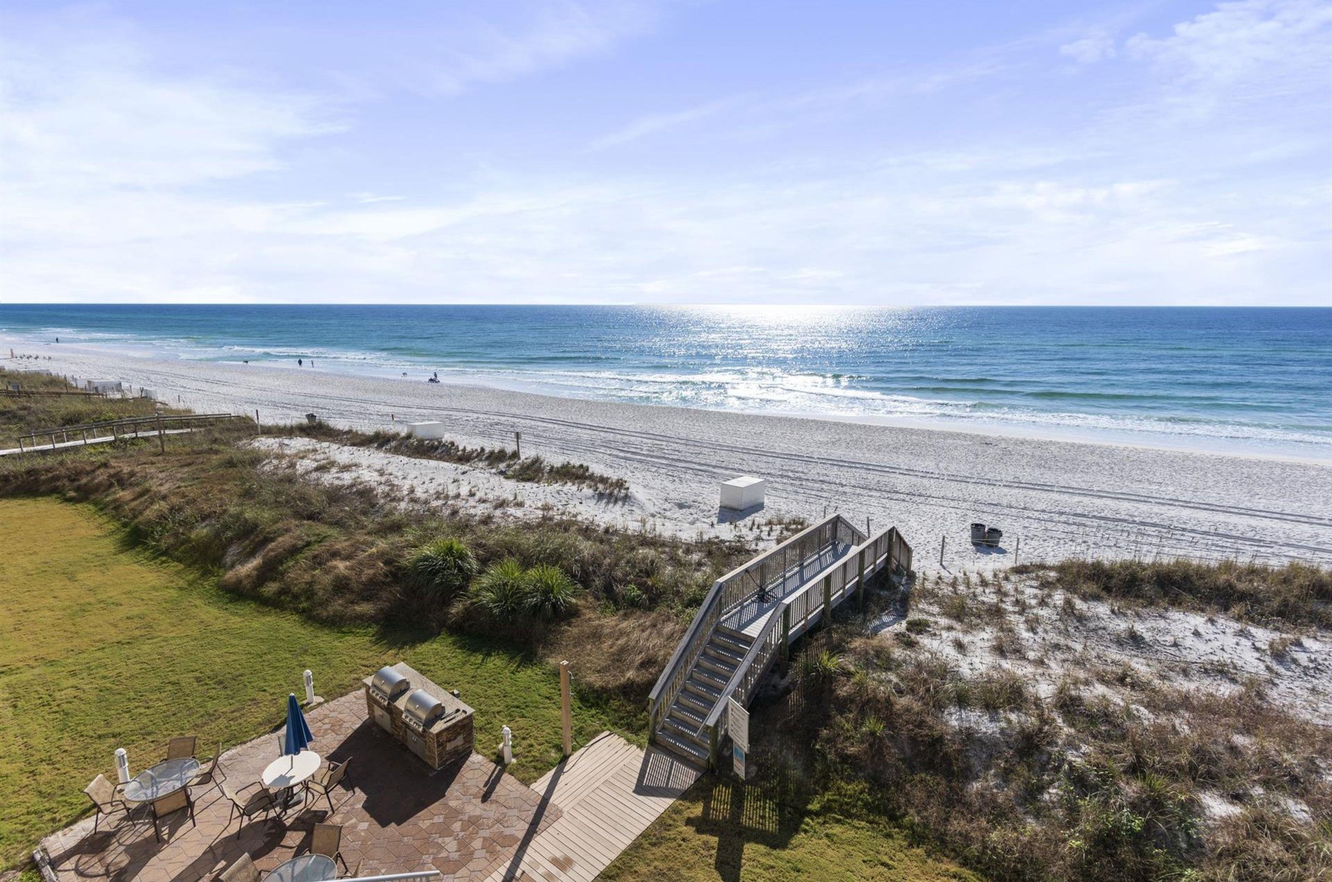 The community has a grilling patio with tables and chairs for picnicing next to a boardwalk to the beach.