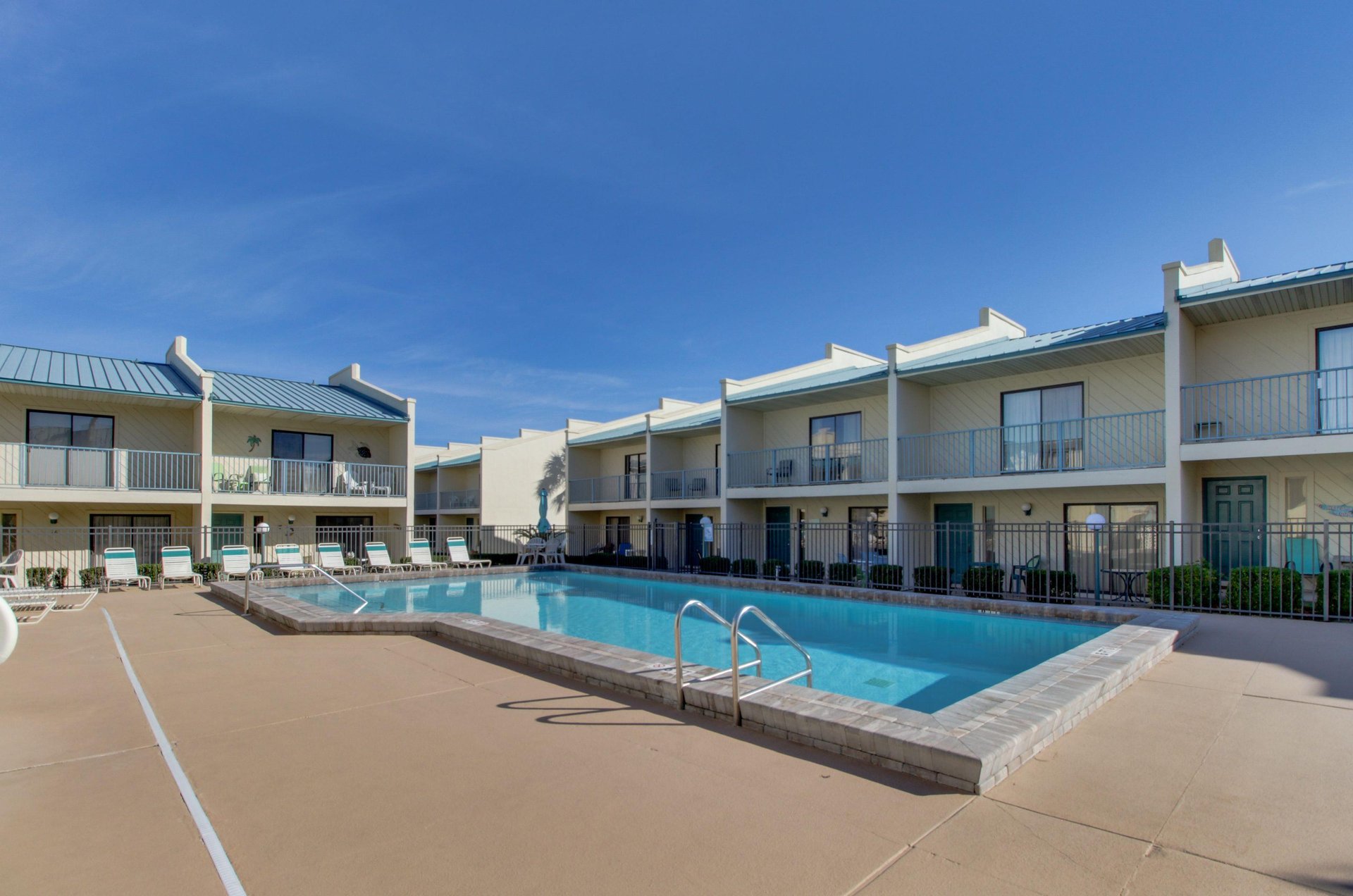 Complex balconies and patios look out over the inviting swimming pool, sundeck and loungers.