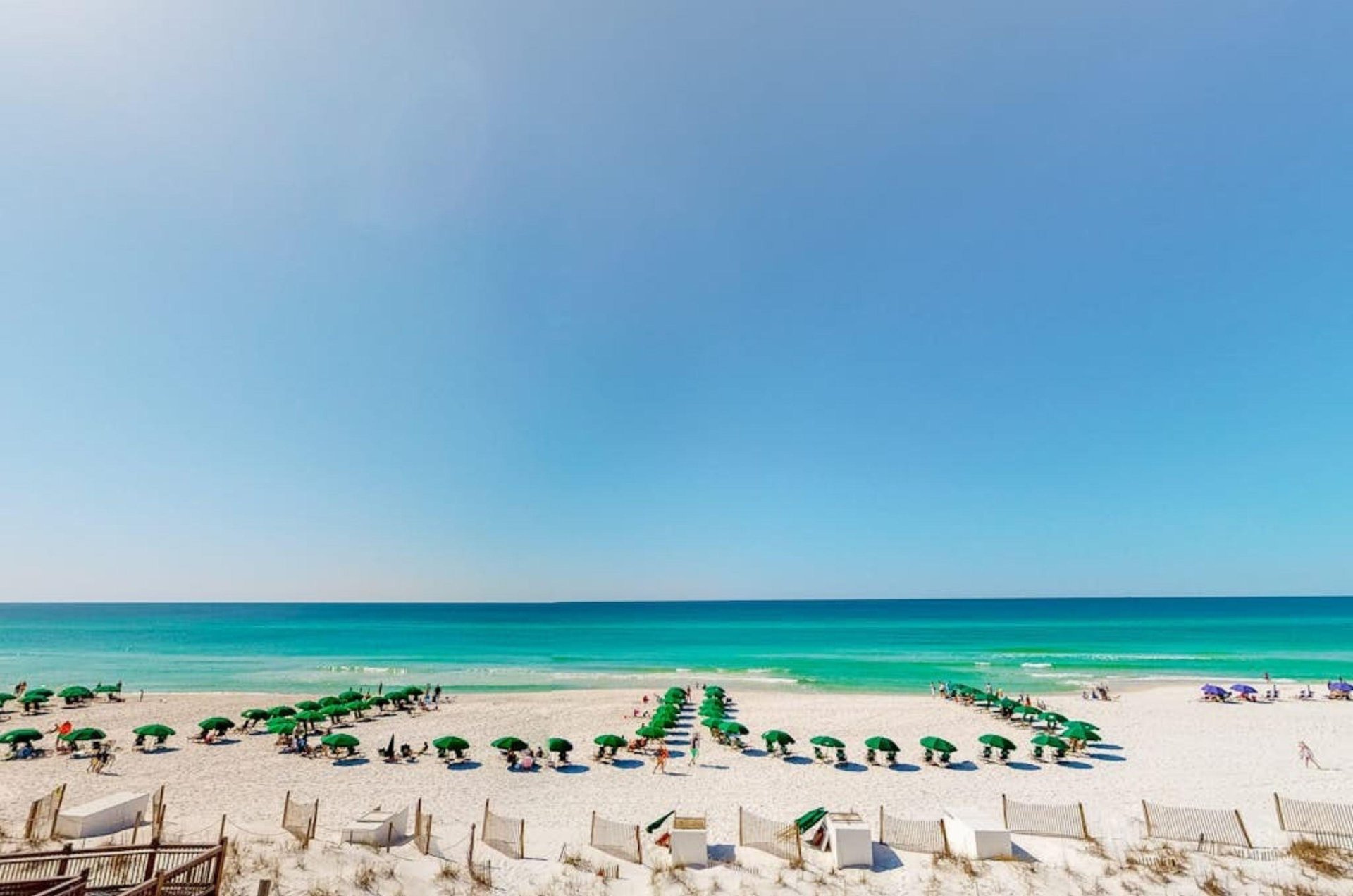 View from a balcony of the private beach with chairs and umbrellsa in front of Waterscape Condos