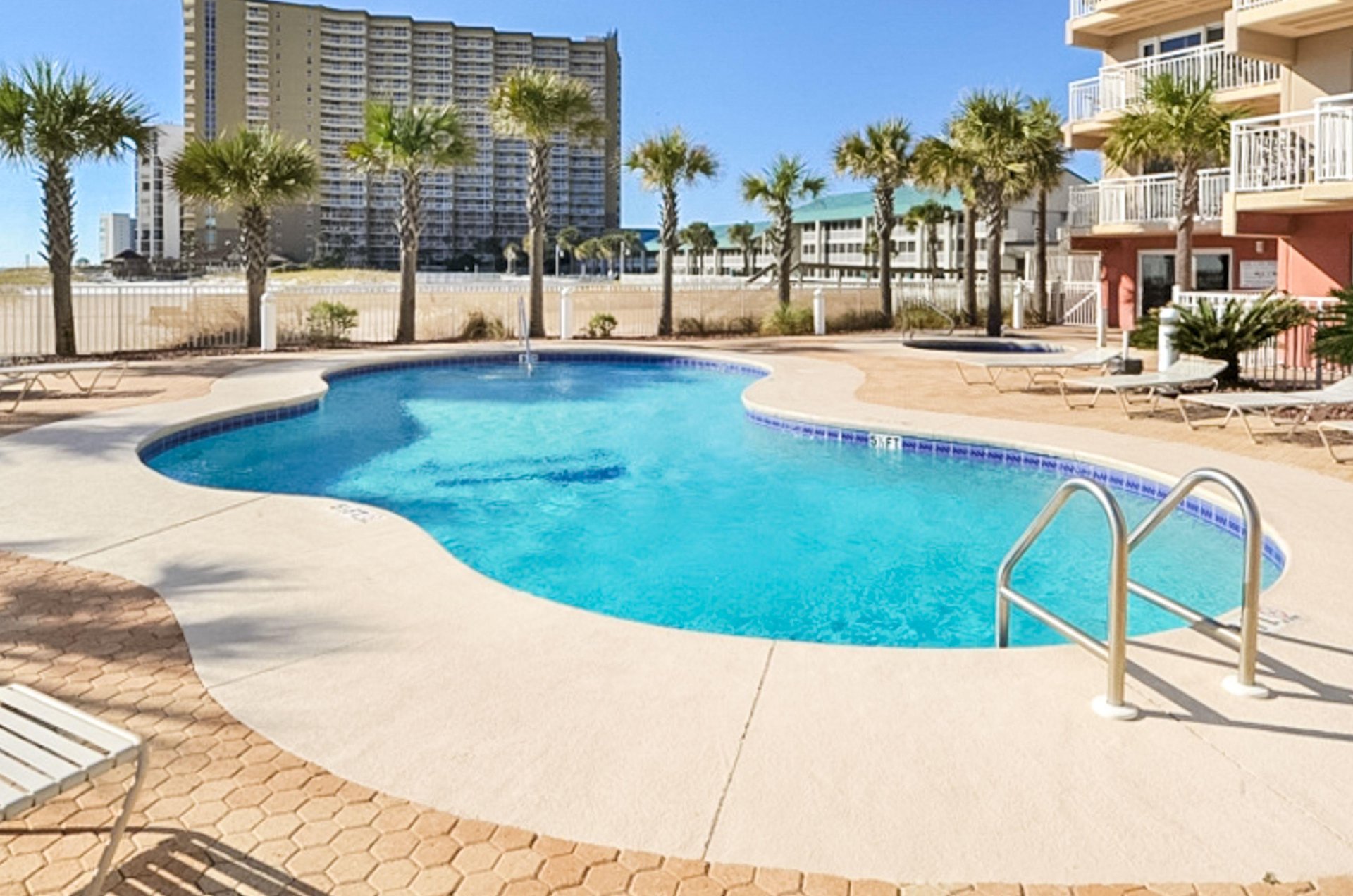 The complexs irregularshaped swimming pool sparkles under blue skies.