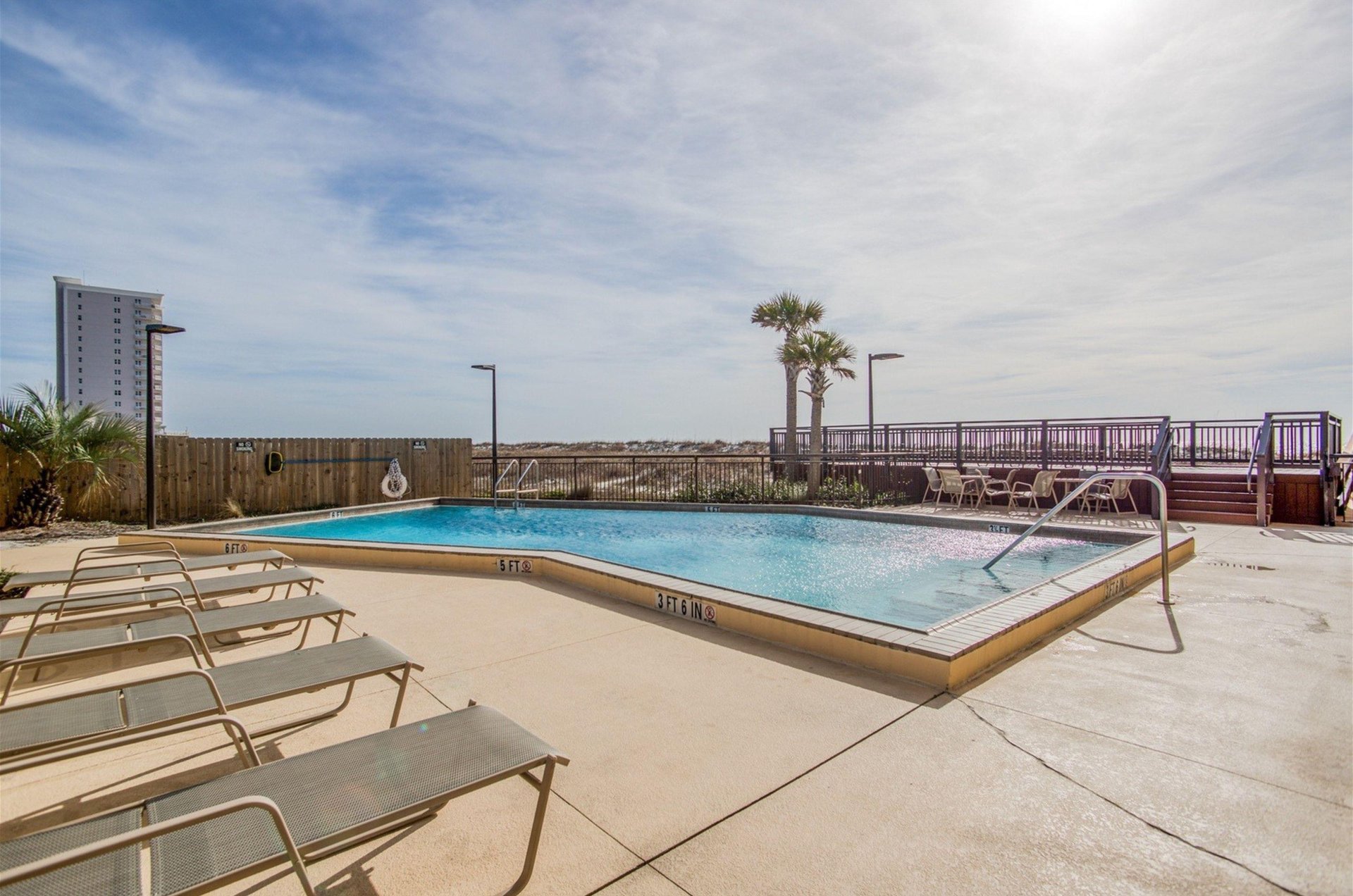 The outdoor pool with lounge chairs overlooking the Gulf at Ocean Breeze West