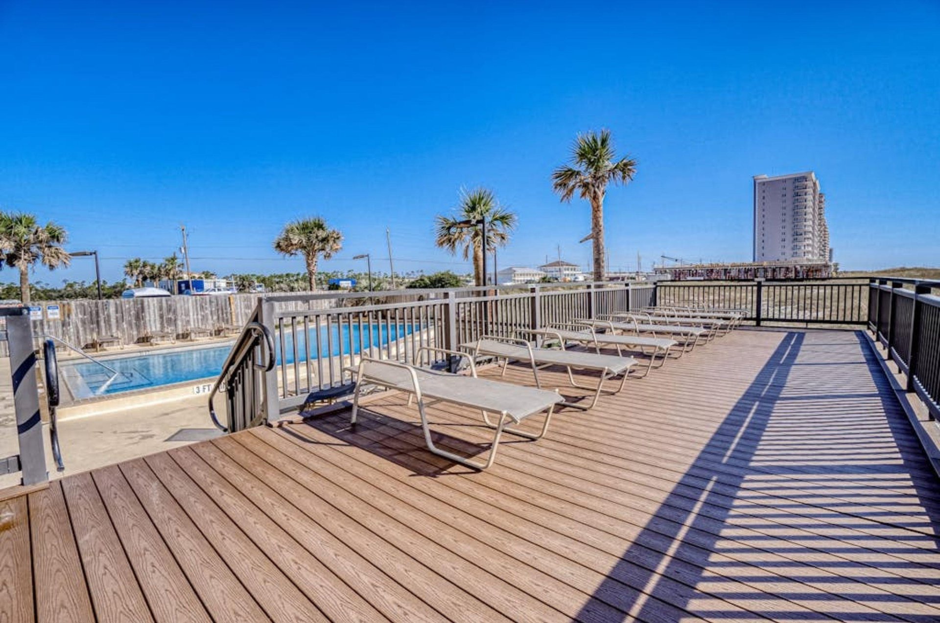 The outdoor patio with lounge chairs next to the swimming pool at Ocean Breeze West