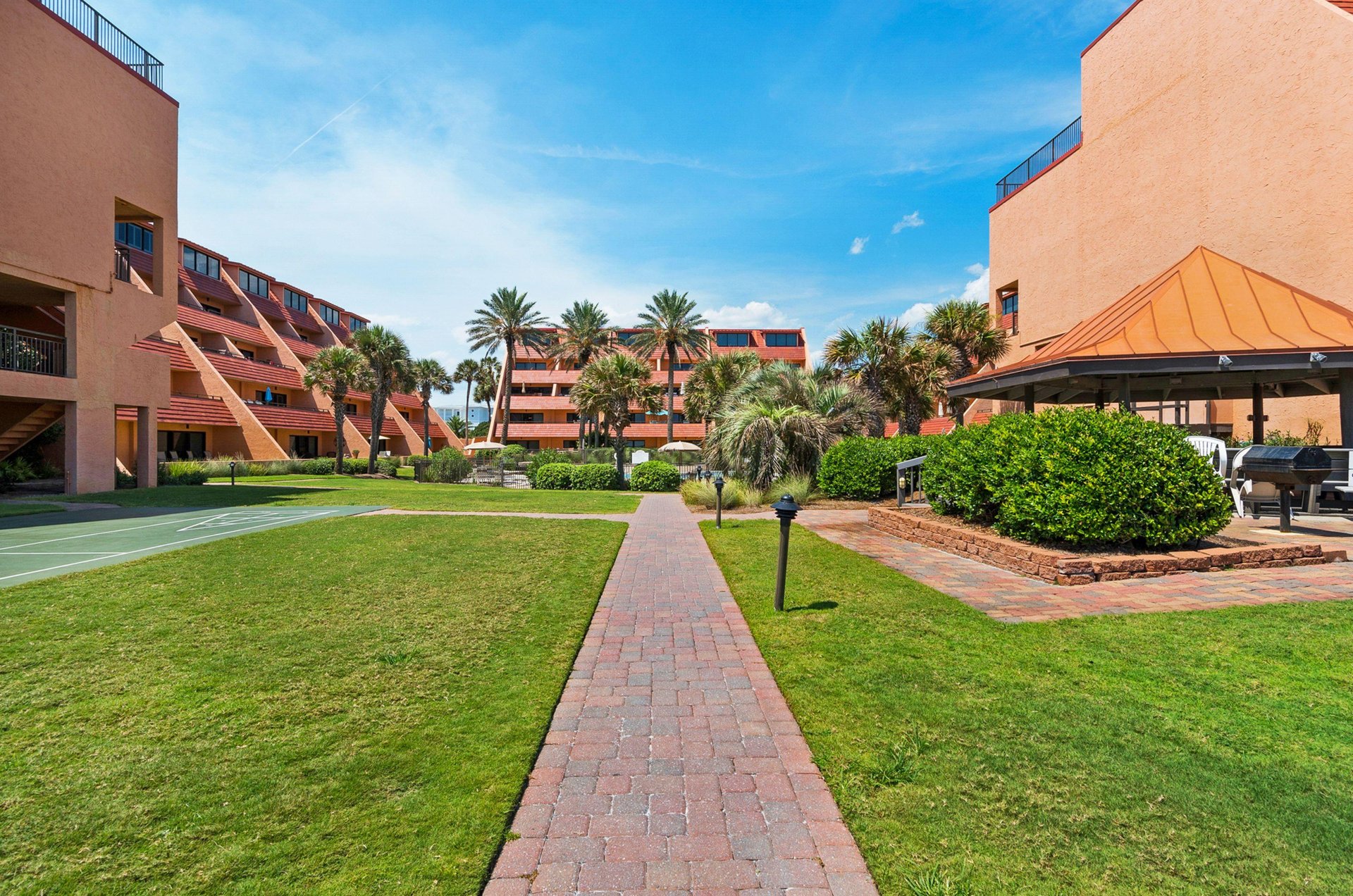 A shuffleboard court set among lush landscaping and brick paths provides guests a fun activity in the tropical setting.