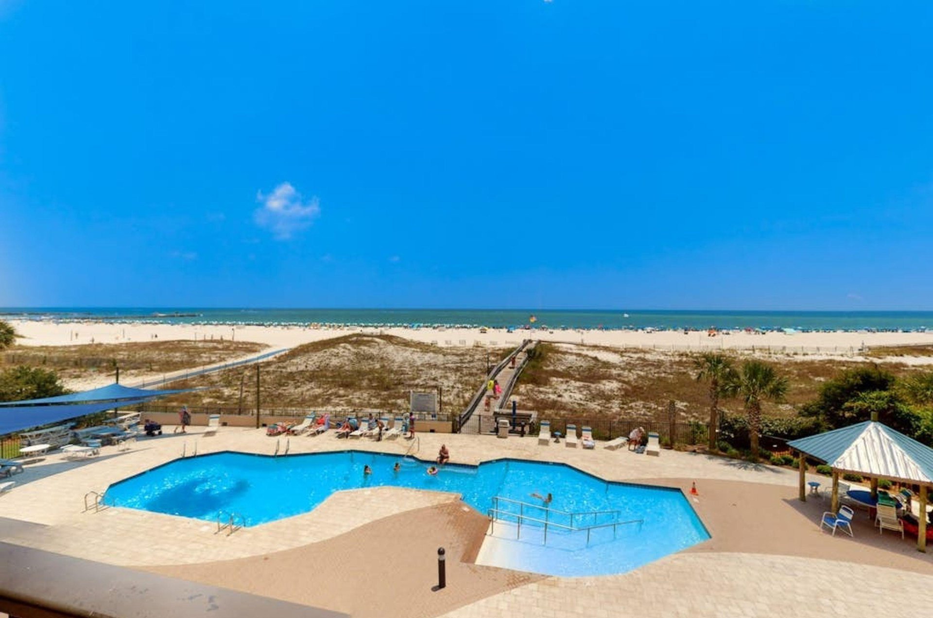 View from a balcony of the outdoor pool and pool deck next to the beach at Phoenix II