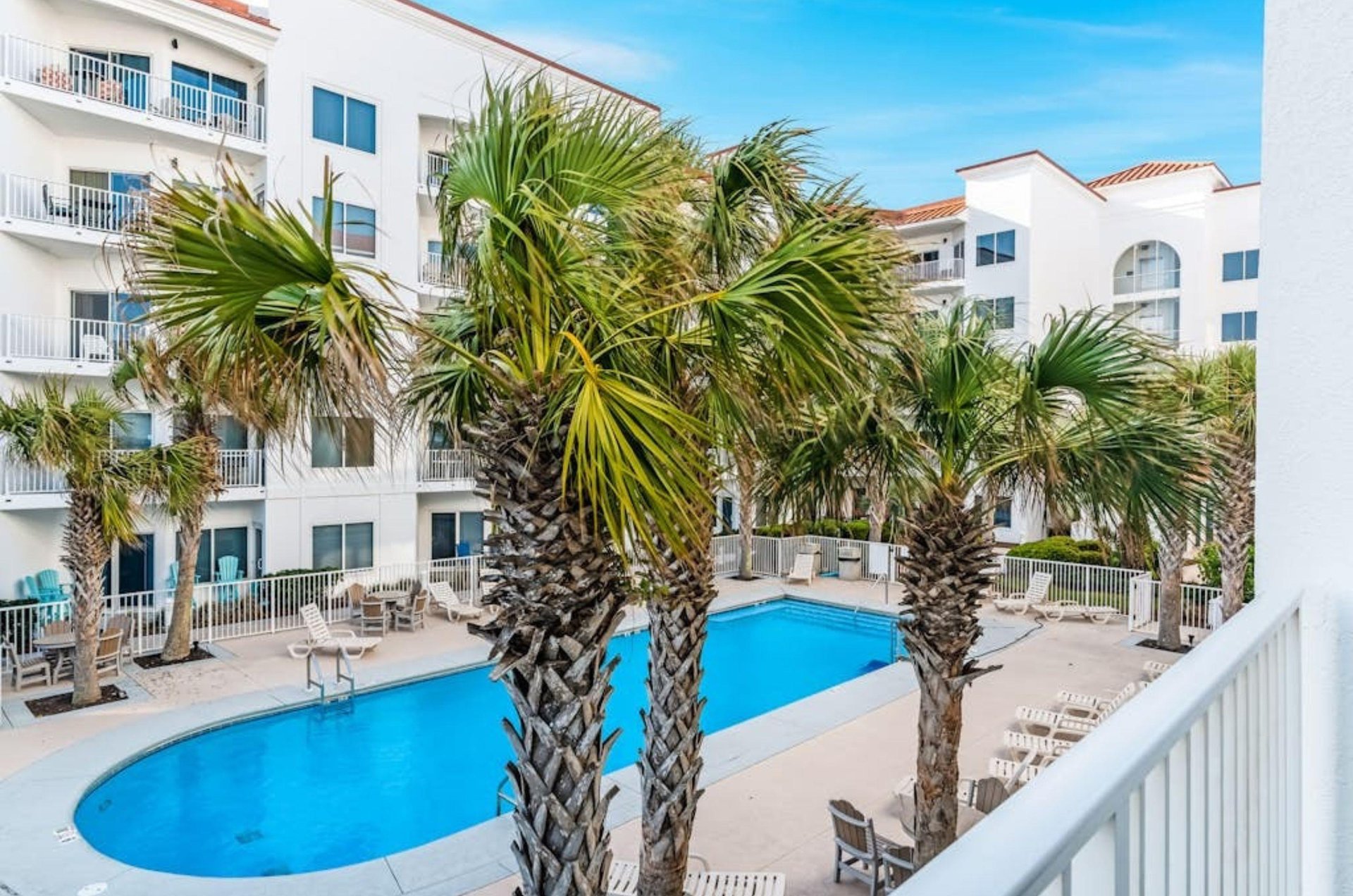 View from a balcony of the courtyard with the outdoor pool and trees at Palm Beach Condos