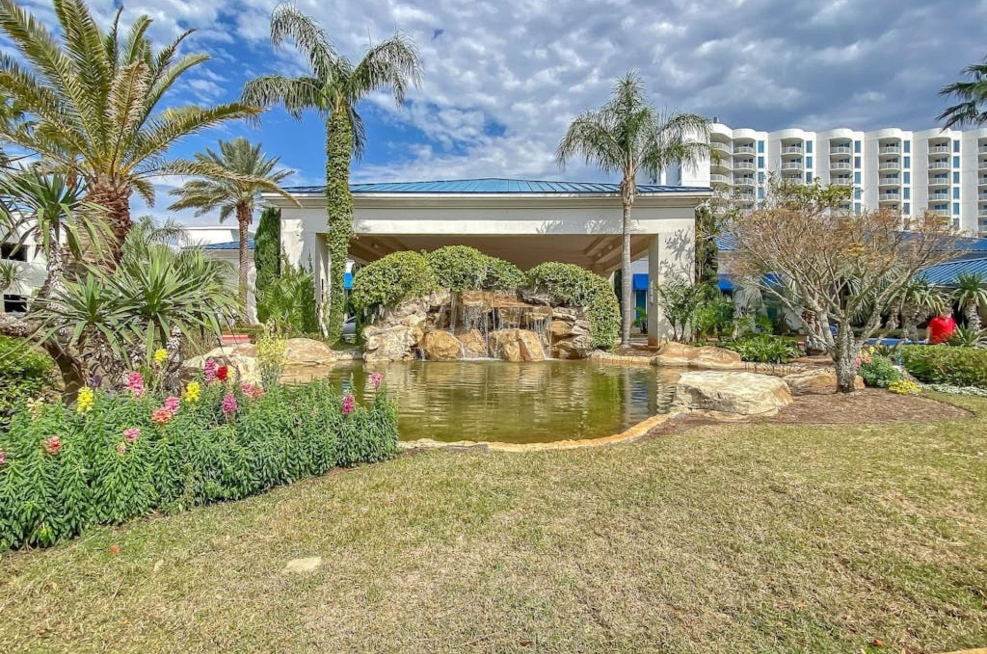 The entrance to the Palms of Destin with a waterfall and palm trees out front