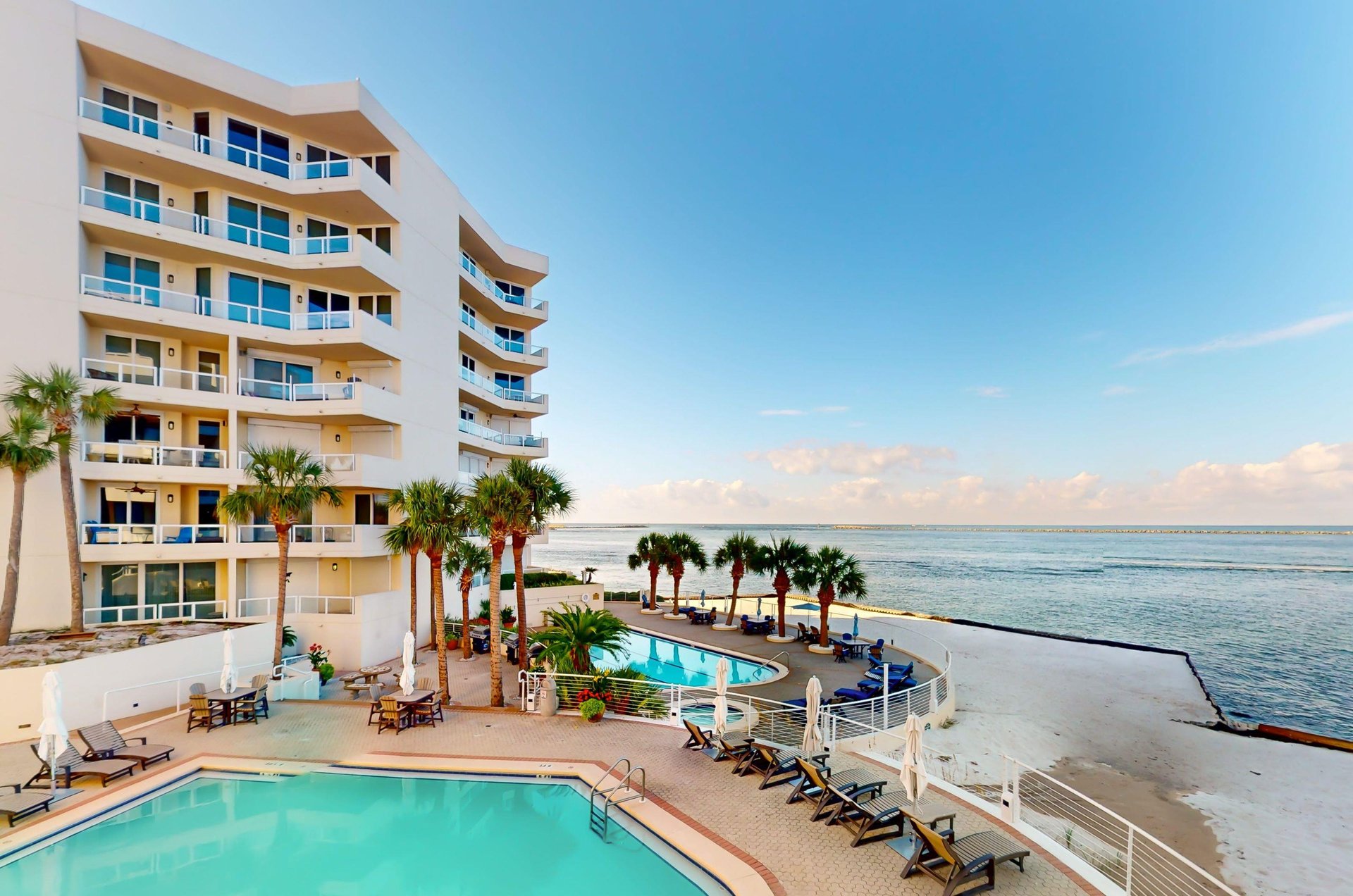 Balconies overlook swimming pools, a hot tub, and the Gulf and East Pass beyond.