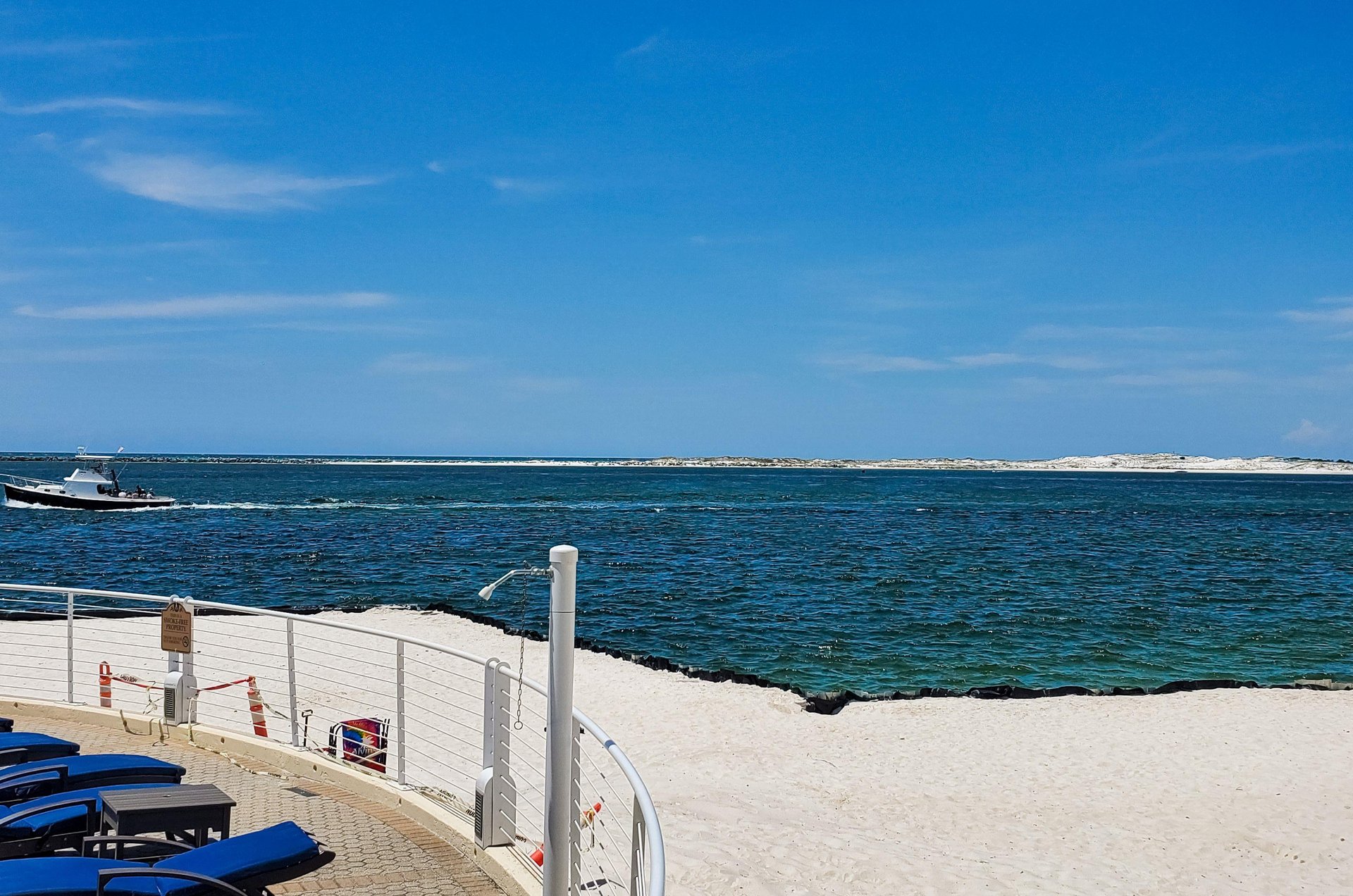 A sandy beach, lounge chairs on a sun deck, and shower for washing off salt and sand alongside East Pass.