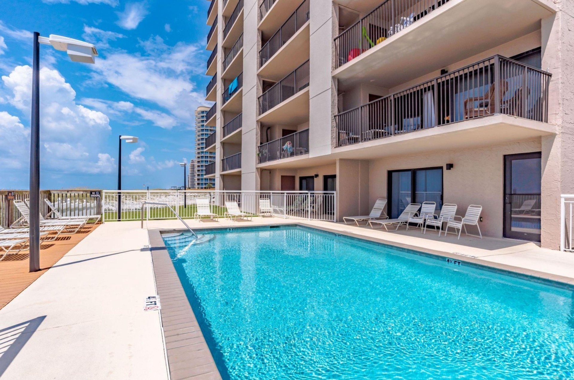 The outdoor swimming pool and pool deck in front of Ocean Breeze East Condominiums