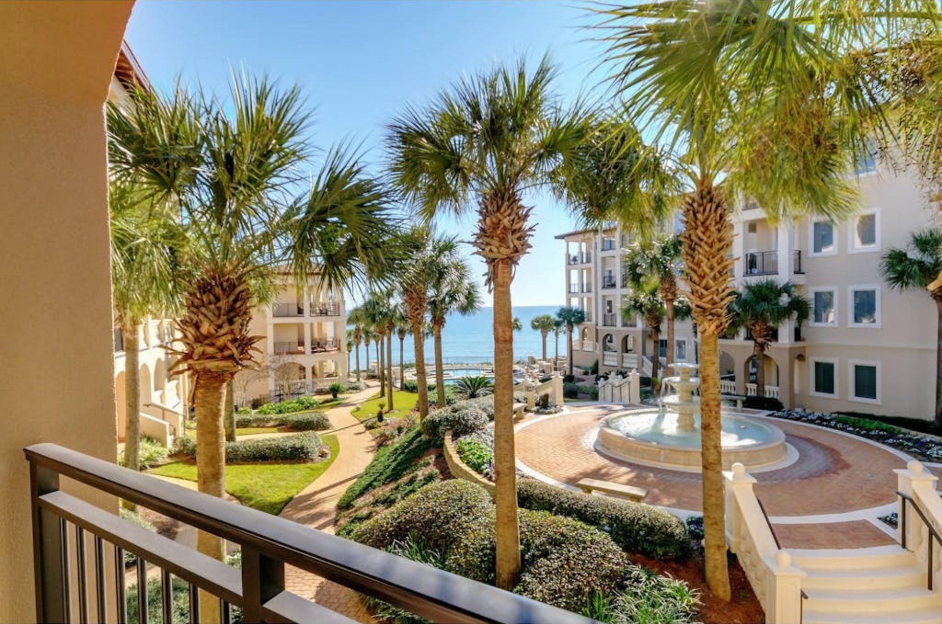 View from a balcony of the piazza and pool deck with a fountain and trees at Bella Vita