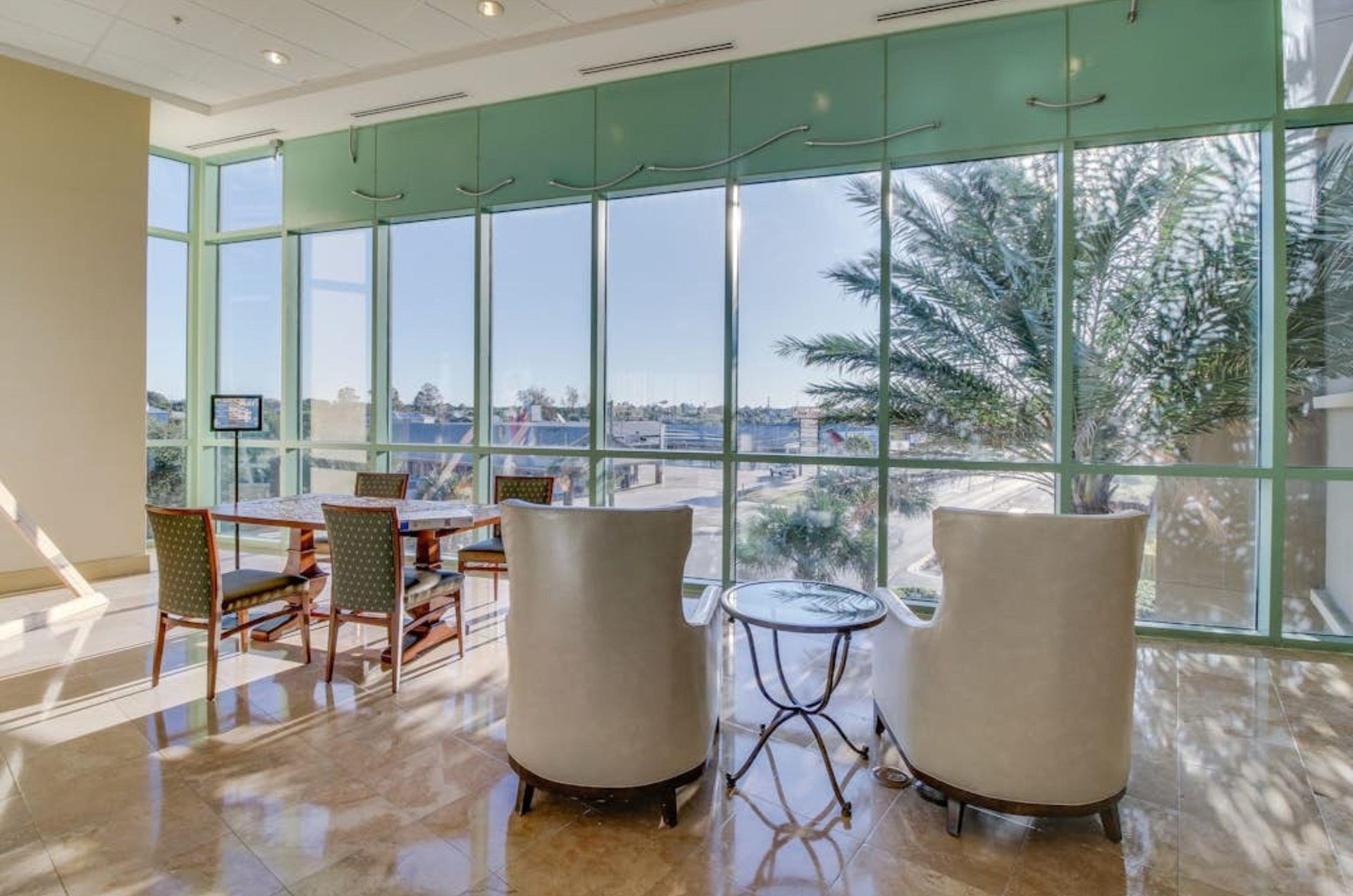 The lobby with chairs next to large windows at Emerald Beach Resort