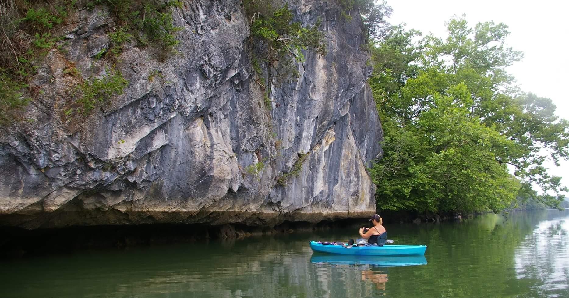 lady kayaking next to a rock face