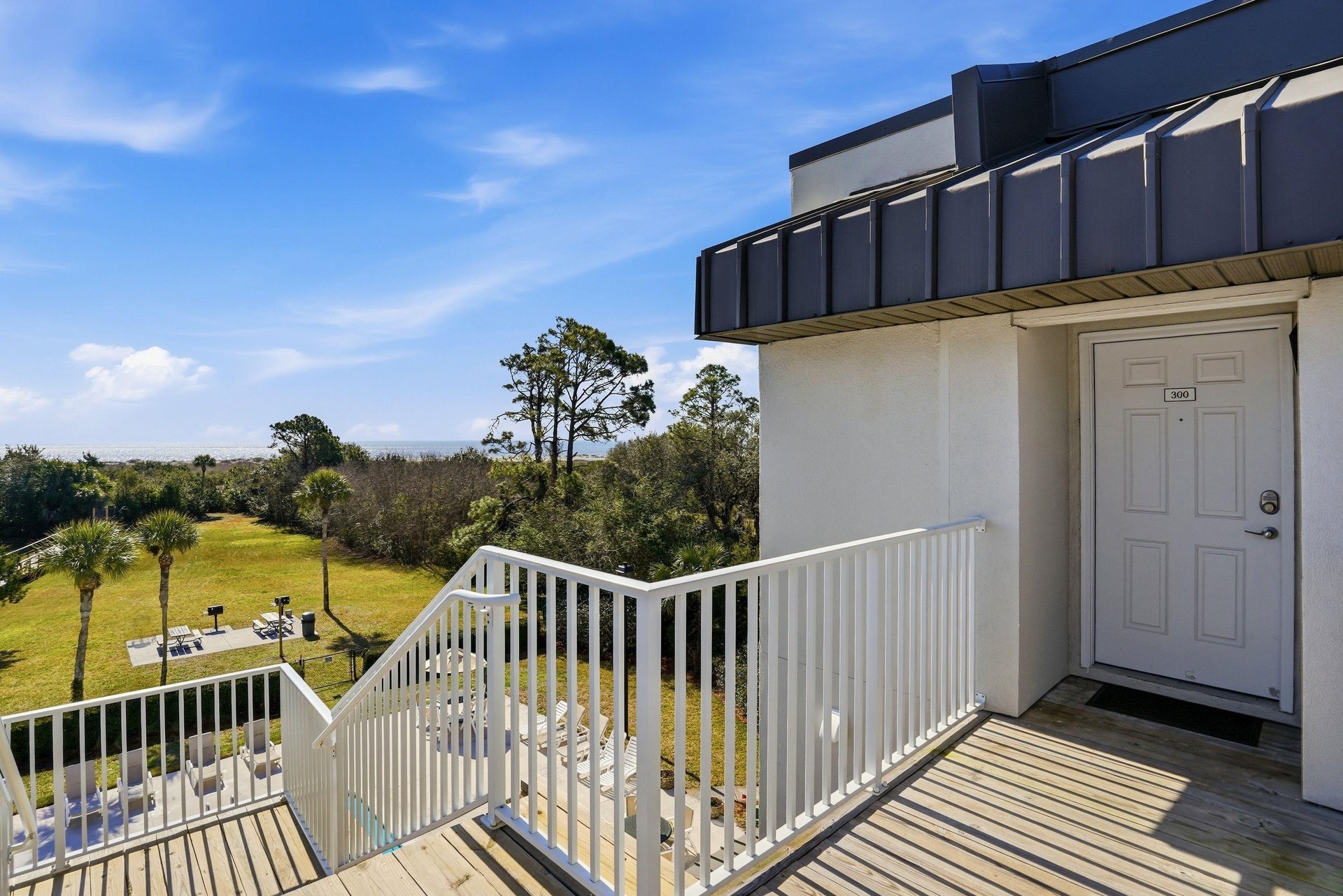 From this topfloor corner entry, enjoy elevated views of the pool, treetops, and nearby beach access path.