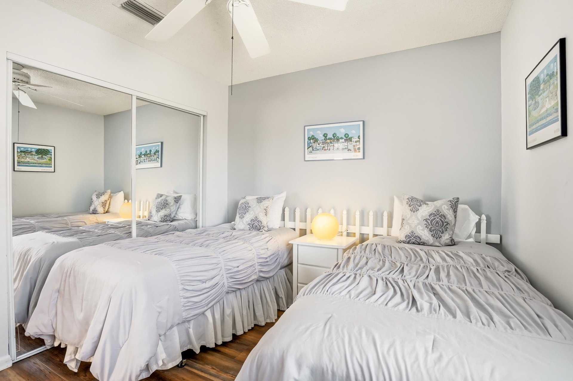 This guest bedroom includes two twin beds and a mirrored closet for storage, with the option to place the beds together for added flexibility.
