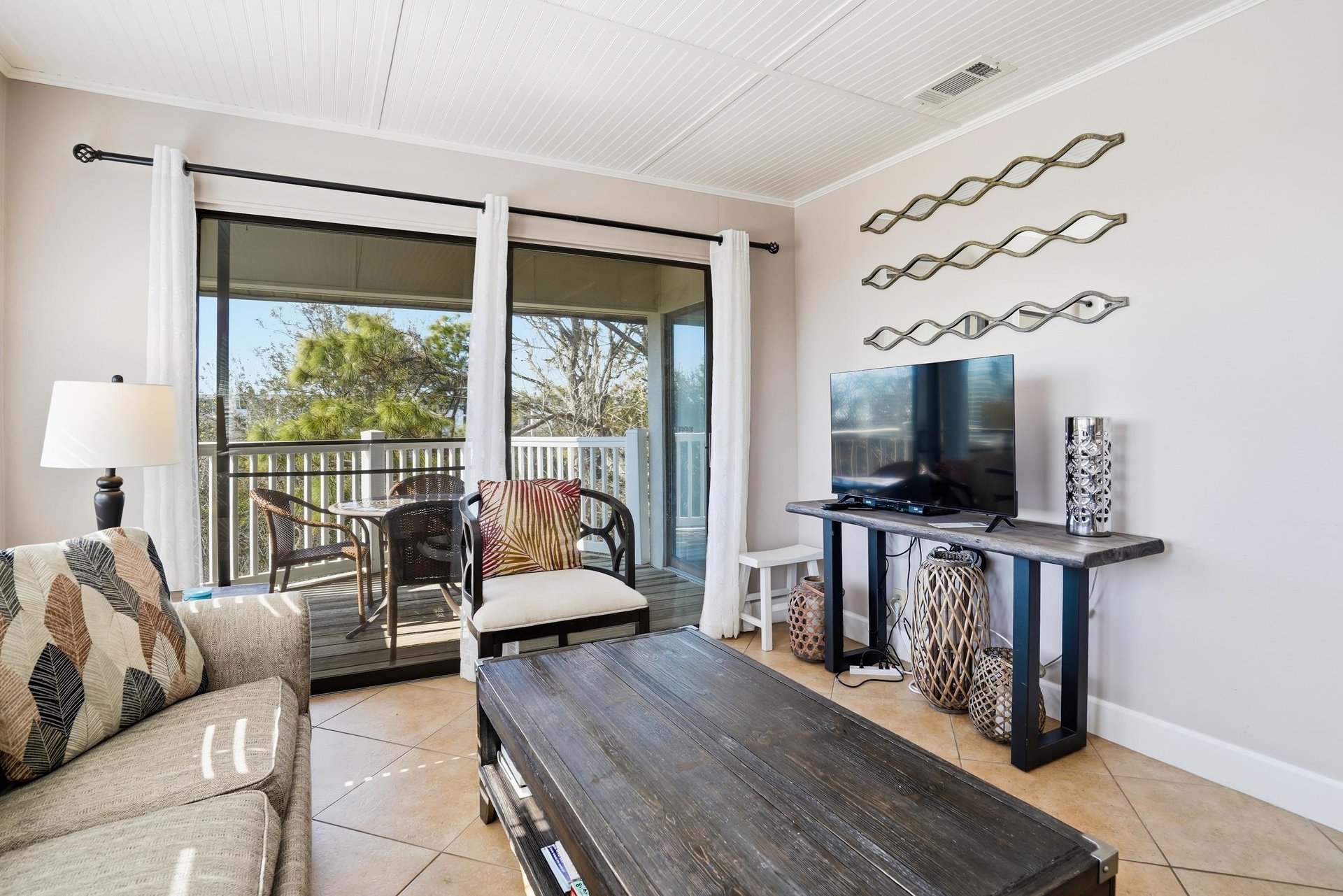 The living area features a TV and easy access to the balcony, creating a comfortable space to relax and enjoy the coastal setting.
