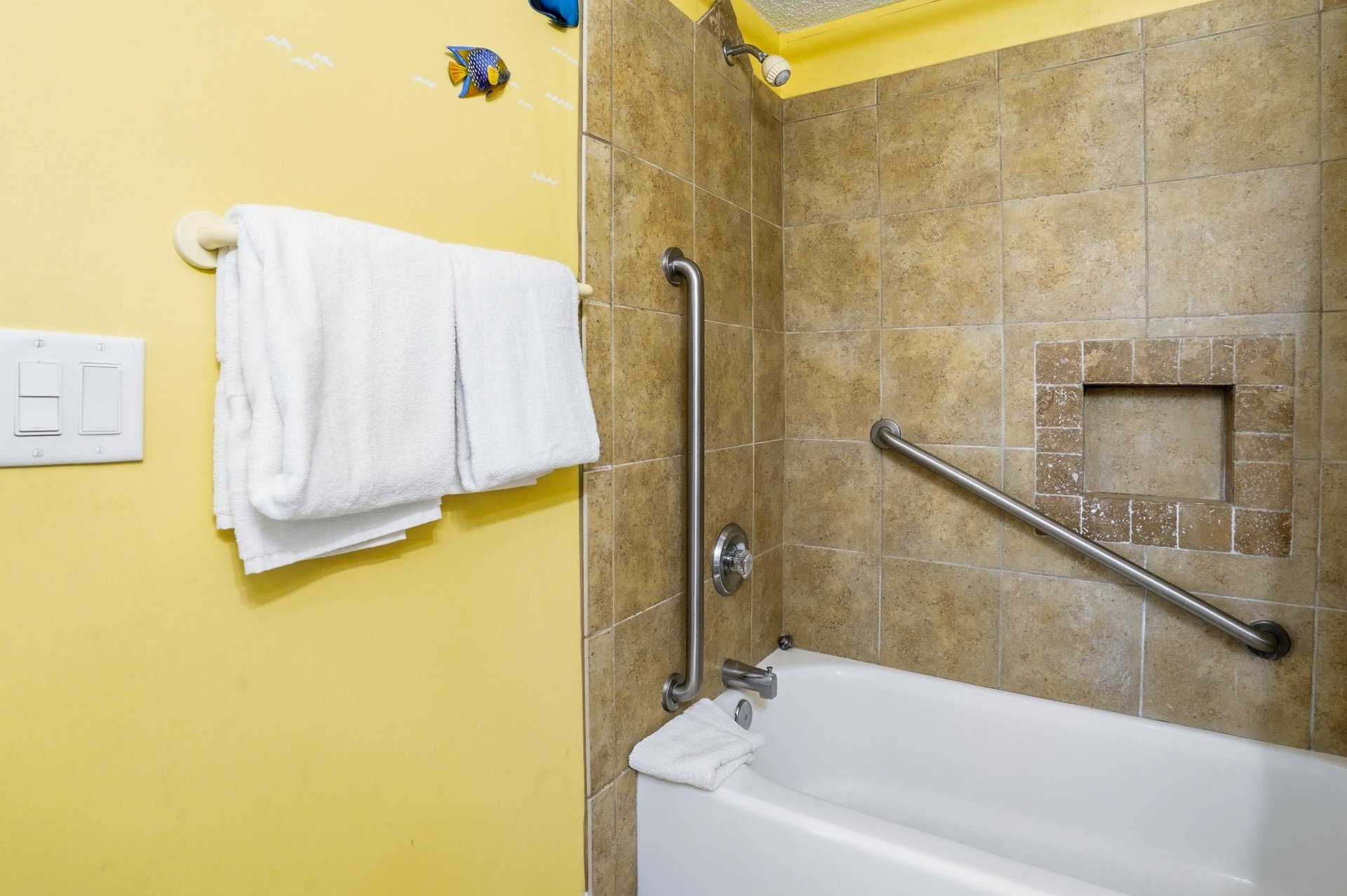 Tiled tub and shower combination with grab bars and builtin storage for added convenience.