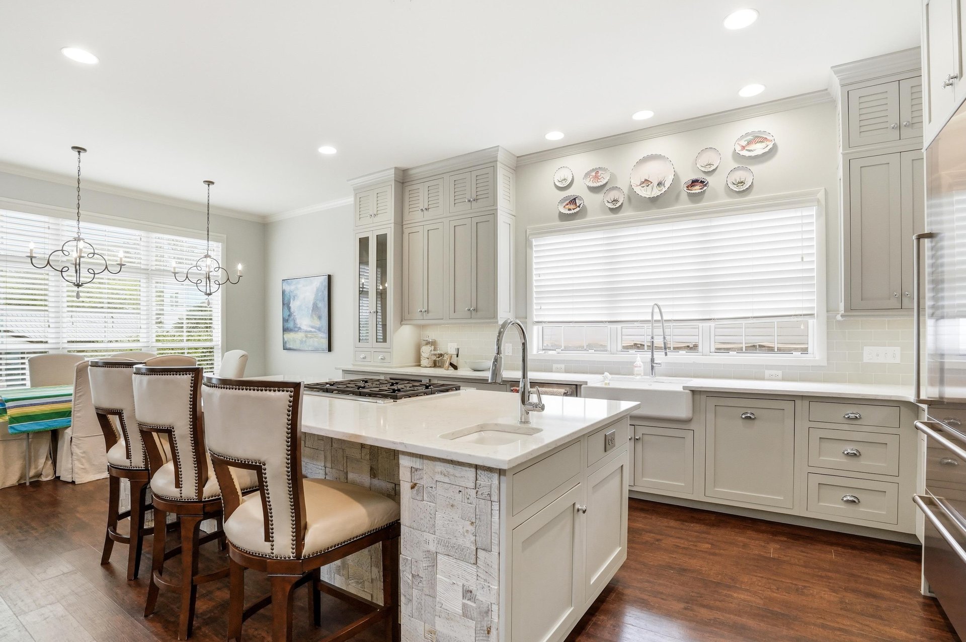 White and gray Shaker cabinets, marble countertops, and a central island with bar seating — a kitchen built for real cooking.