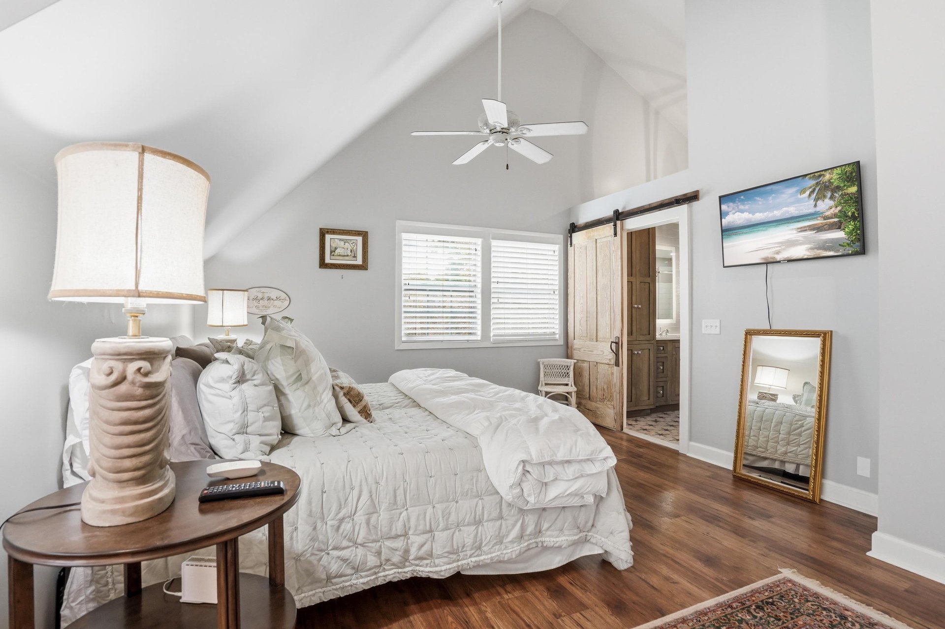 King bed, wallmounted TV, and a goldframed mirror — a bedroom that works equally well for adults who want to wind down in private.