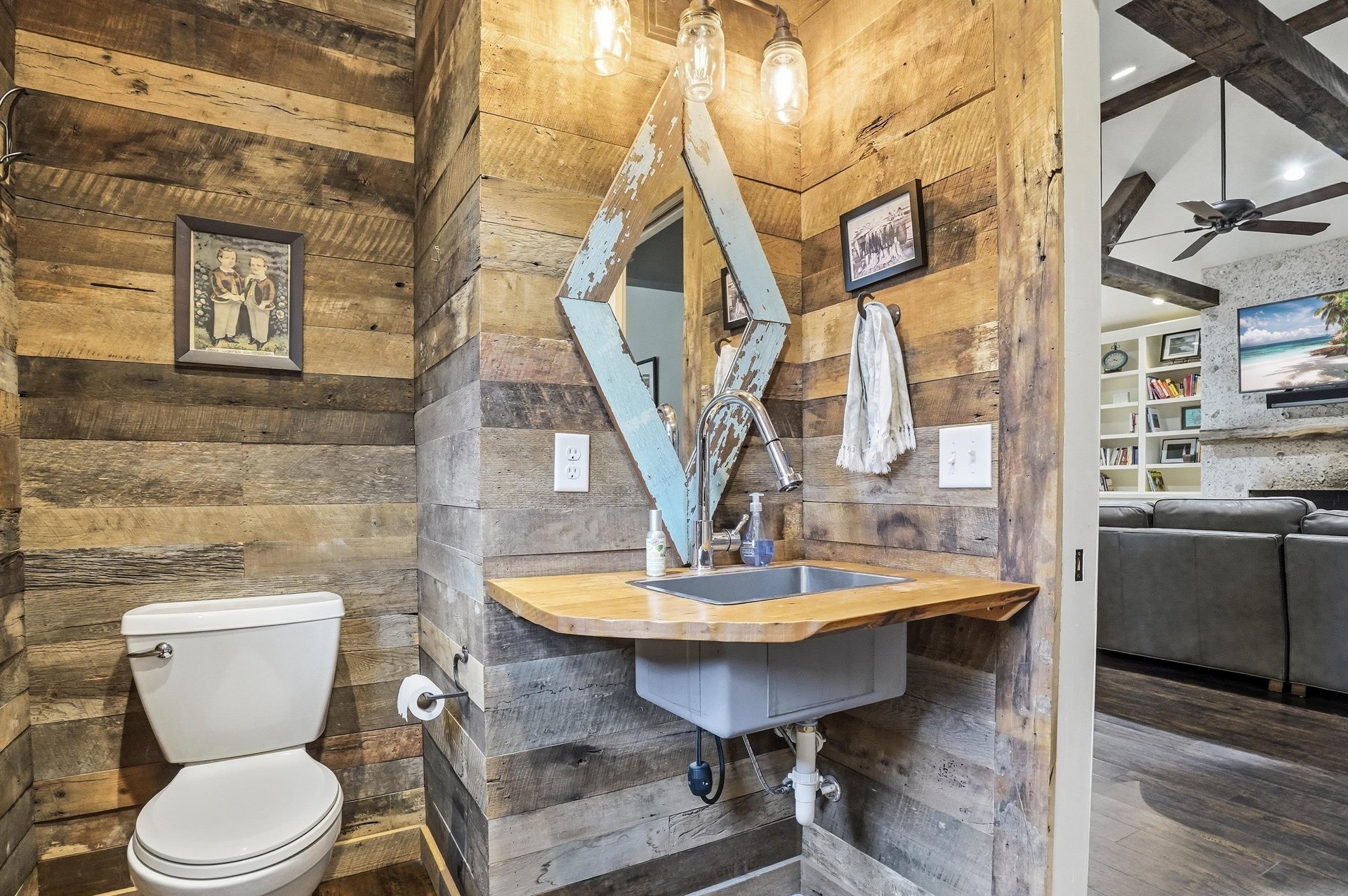 Reclaimed wood accent wall, floating vanity, vessel sink, and industrial pendant lights.
