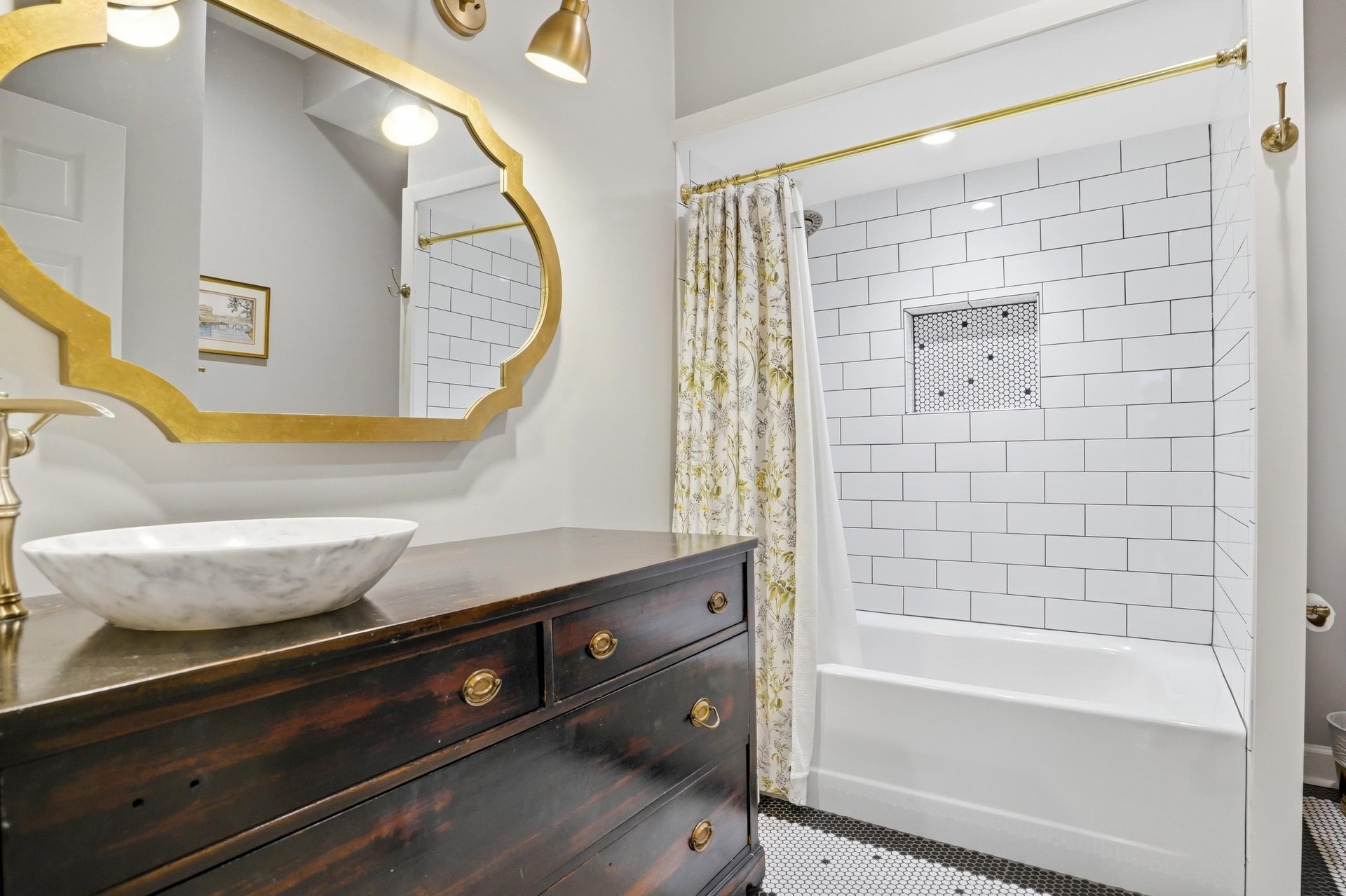 Dark wood vanity, vessel sink, gold hexagonal mirror, and white subway tile — this bathroom has a point of view.