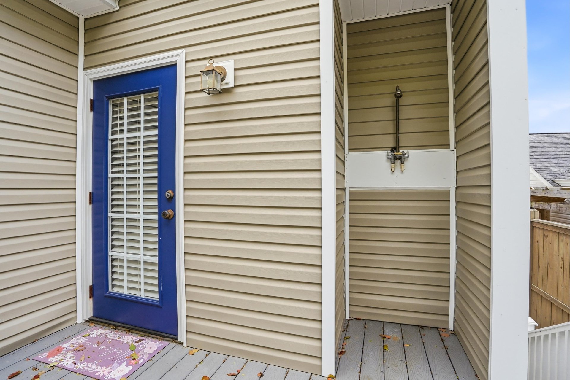 The back entrance detail — same confident blue door, exterior shutters, and a welcome mat that means what it says.