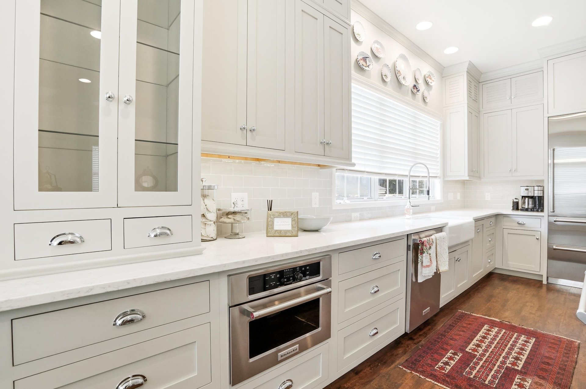 Glassfront uppers, a builtin double oven stack, and a Persian rug grounding the space — thoughtful from countertop to floor.