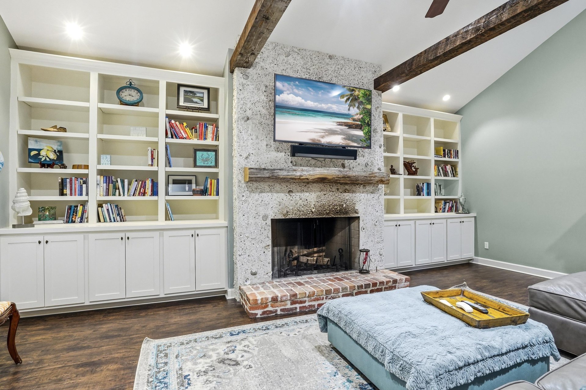 The full fireplace feature wall — stone surround, TV above, and floortoceiling builtins on both sides.