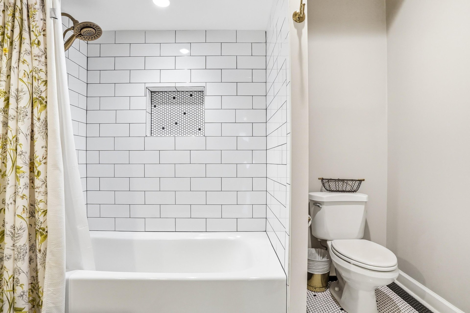 Tub and shower behind a botanical curtain, flanked by white subway tile — classic bones with a distinctive finish.