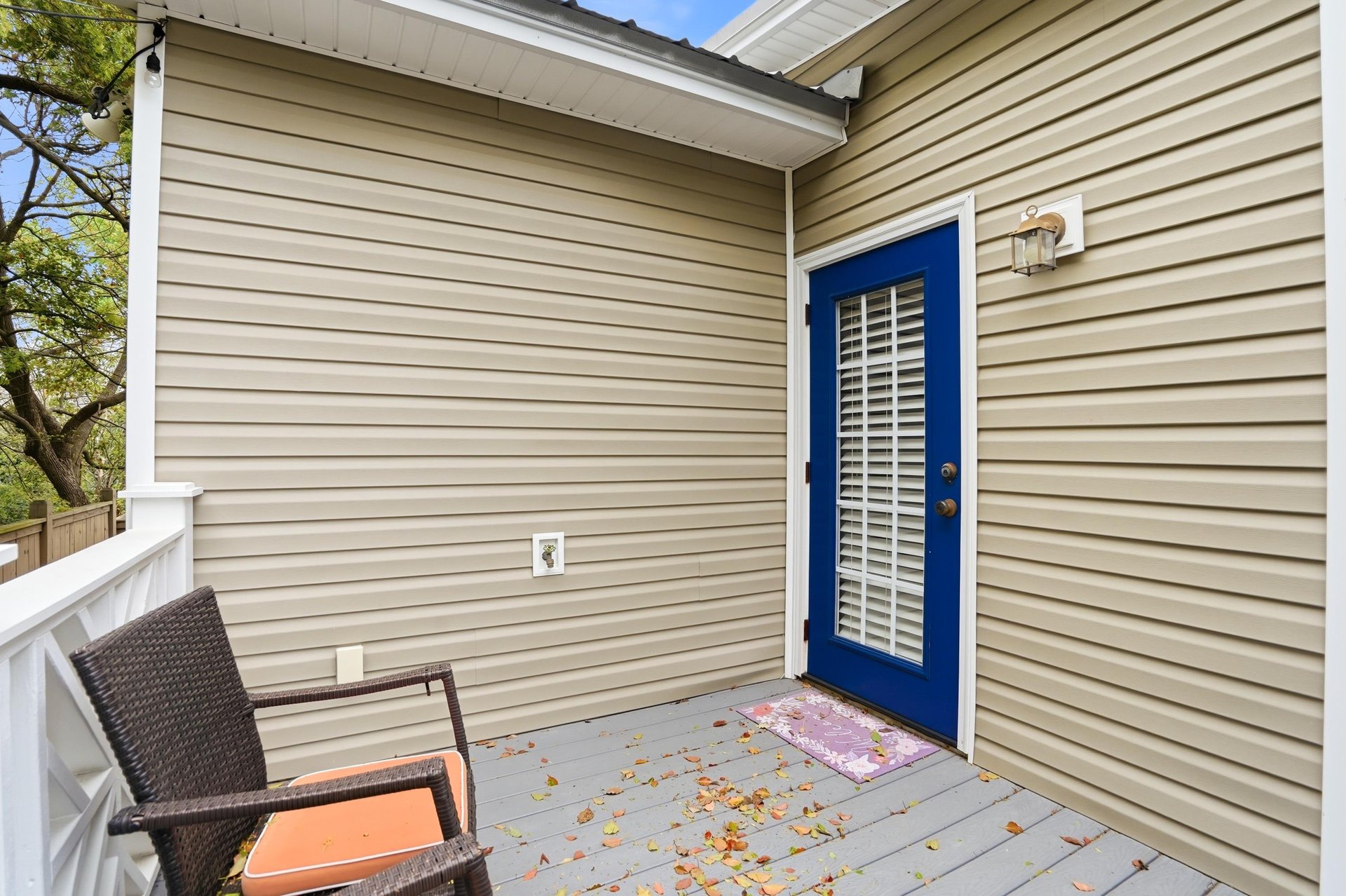 The rear of the home — a blue back door that mirrors the front, a private deck, and green everywhere you look.