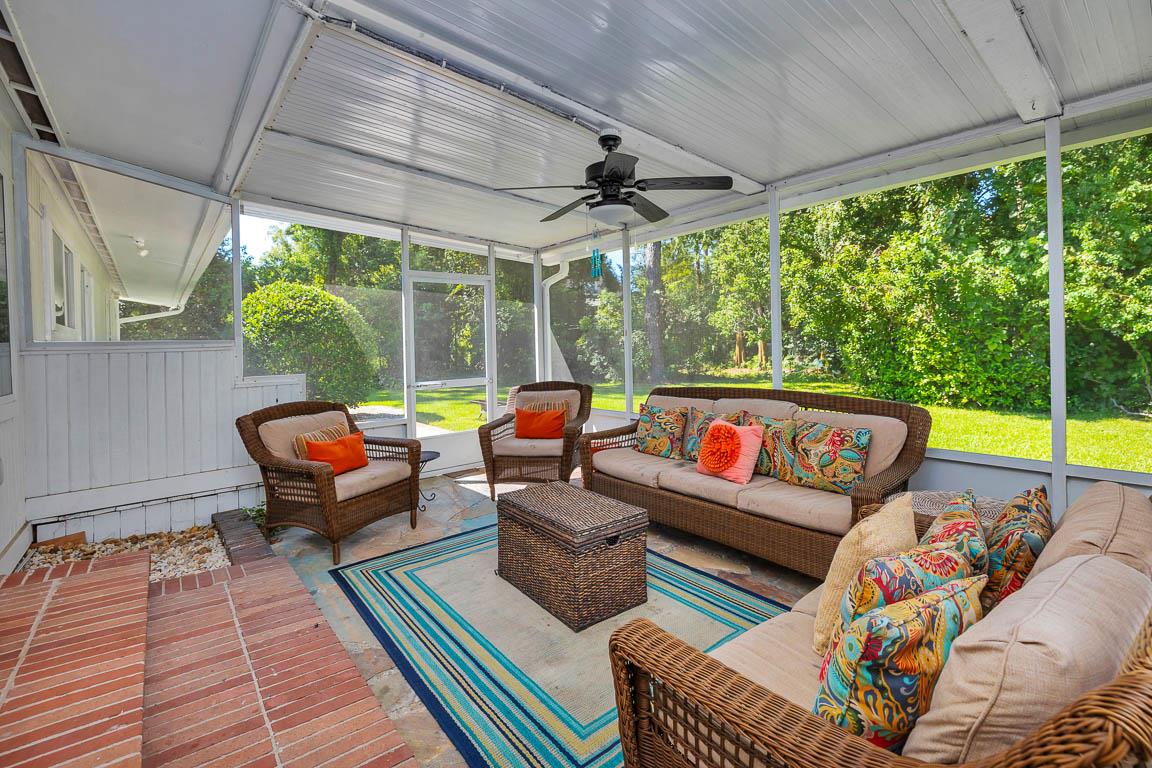 Screenedin porch at 530 Delegal showing multiple seating areas, ceiling fan, and views across the yard from the main house living room.