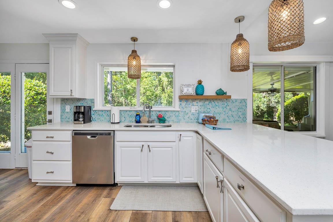 View of the main house kitchen at 530 Delegal showing extended countertop workspace, cabinetry, sink area, dishwasher, and windows looking toward the screened porch.