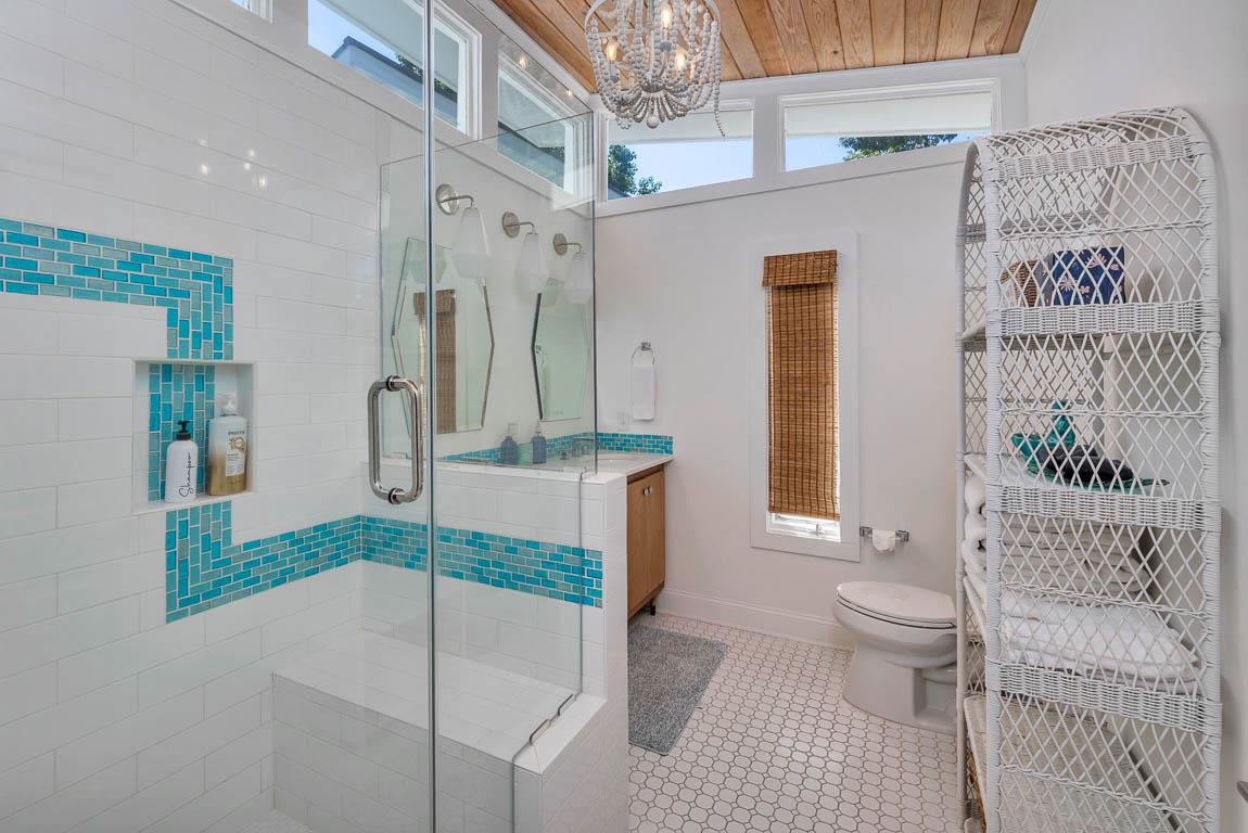 Primary bathroom at 530 Delegal showing a dual vanity, walkin shower with glass enclosure, tiled shower surround, and natural light from upper windows.