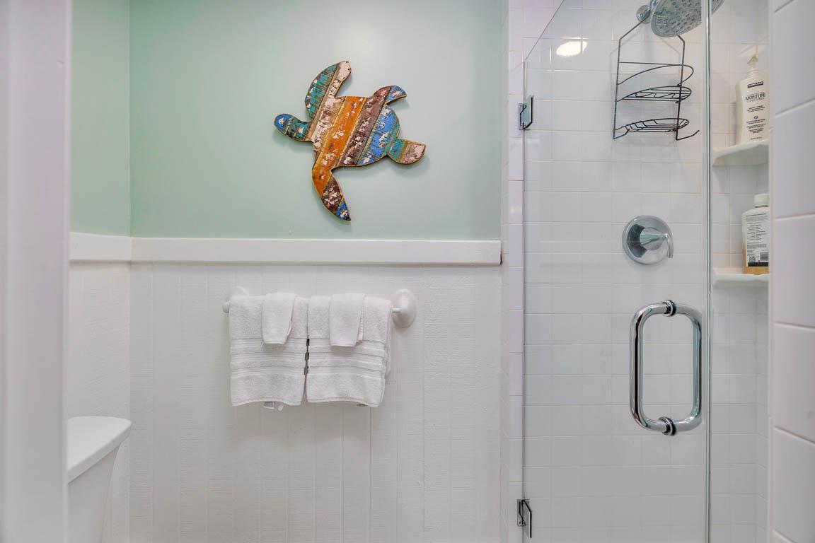 Guest house bathroom at 530 Delegal showing a walkin glass shower with tiled walls, builtin shelving, and towel storage.