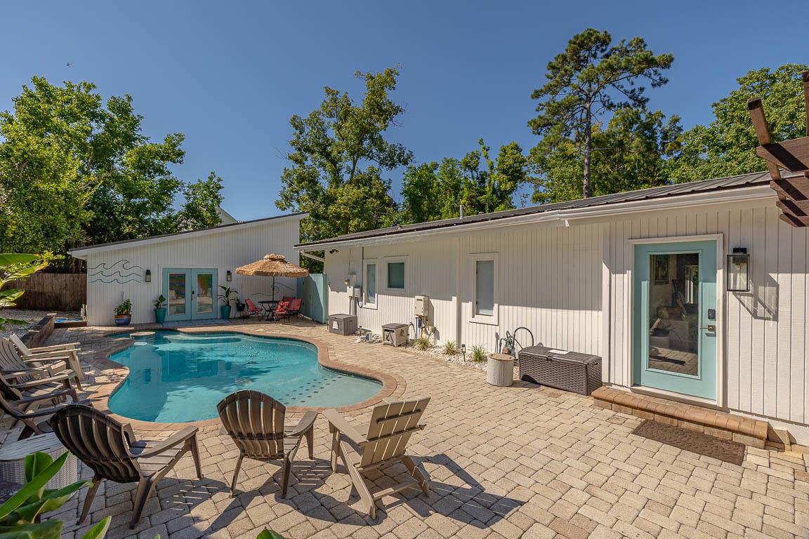 Groundlevel view of 530 Delegal showing exterior doors opening directly onto the paver courtyard and heated pool with adjacent seating.