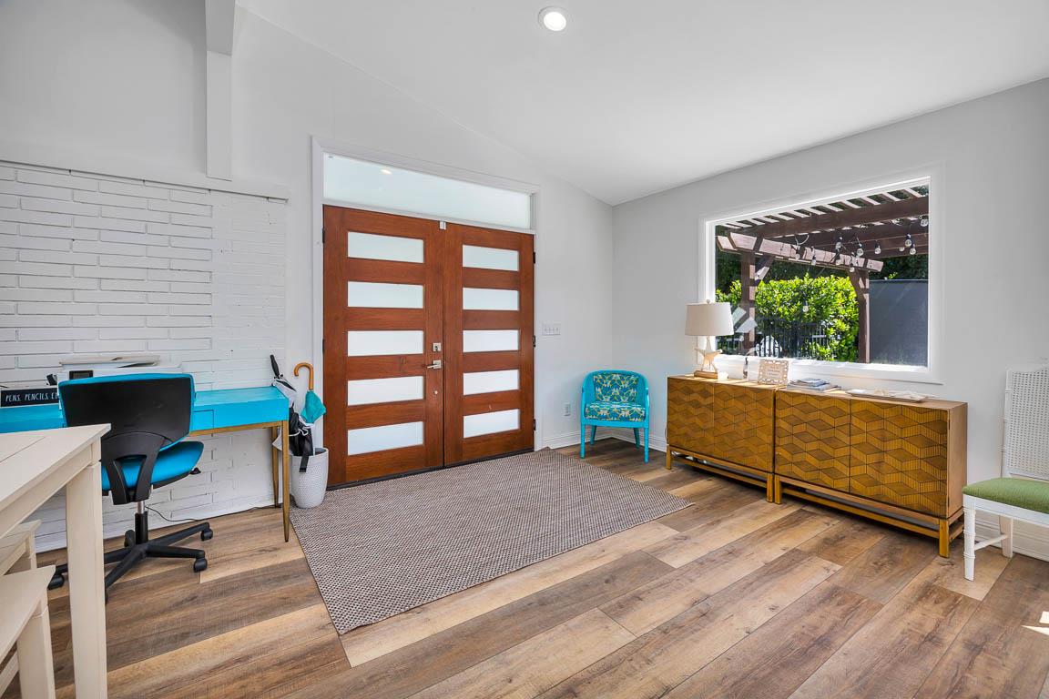 Entryway into the main house at 530 Delegal opening directly into the living room, with wood floors, modern front door, and courtyardfacing window.