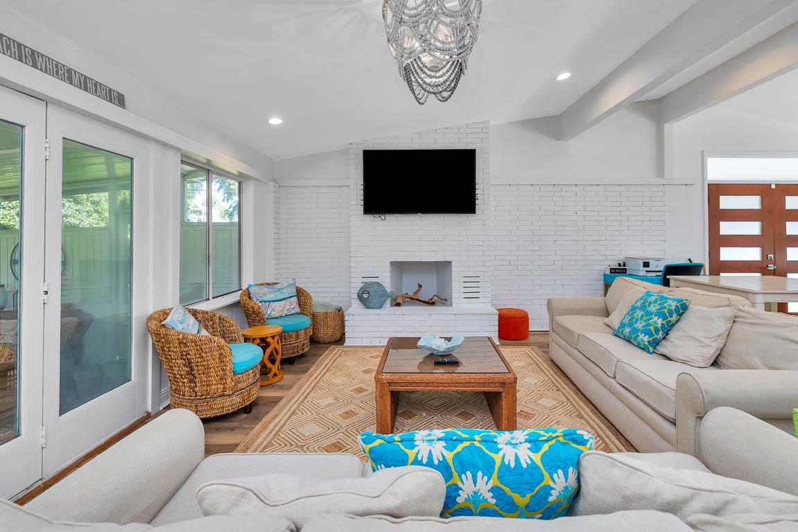 Main house living room at 530 Delegal showing multiple seating areas, fireplace, television, and large glass doors opening toward the screened in porch.