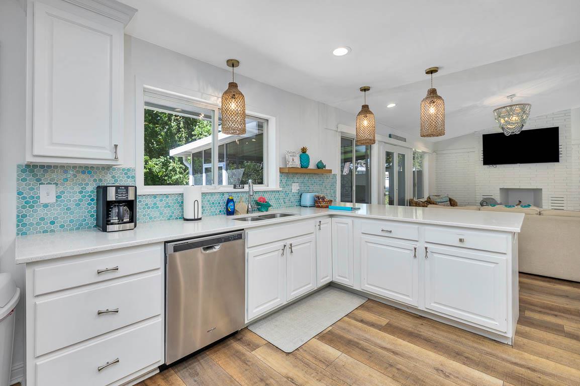 Alternate view of the main house kitchen at 530 Delegal showing wraparound counters, breakfast bar seating, sink and dishwasher, and open sightlines to the living room.