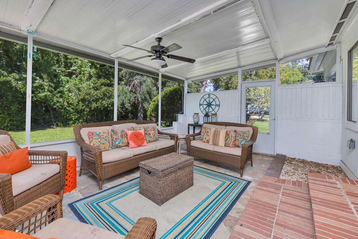Screenedin porch at 530 Delegal showing covered seating, ceiling fan, and direct access from the main house living room.