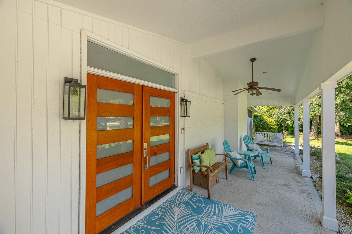 Front porch entry at 530 Delegal showing double front doors, covered porch seating, porch swing, and ceiling fan along the main house entry.