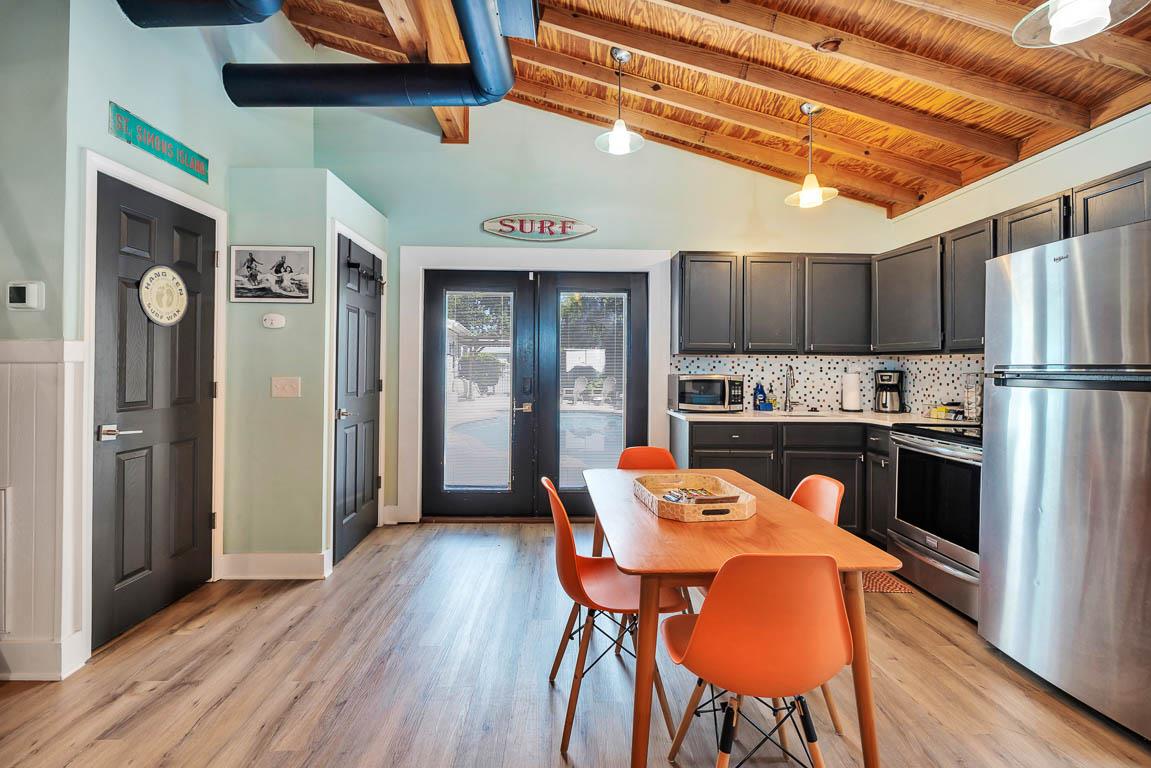 Guest house kitchen at 530 Delegal showing dining table, fullsize appliances, cabinetry, wood flooring, and doors opening toward the courtyard.