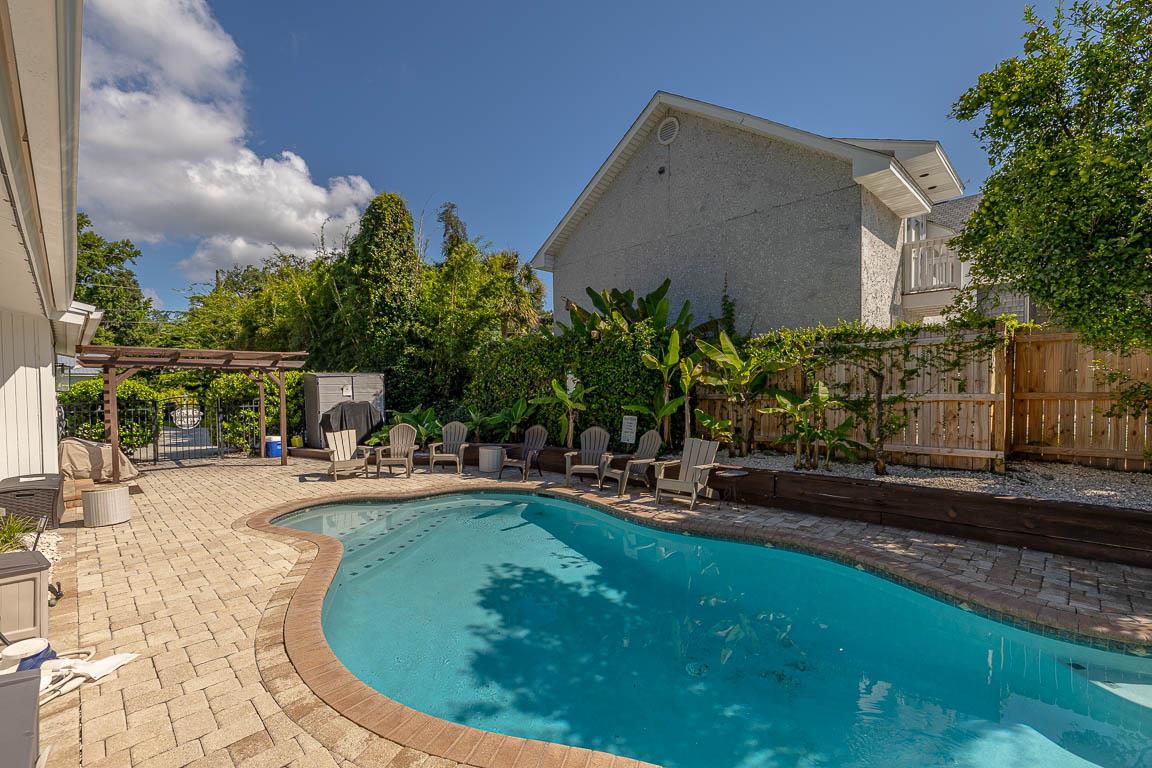 Groundlevel view of the heated pool at 530 Delegal showing the length of the pool, paver deck, lounge seating, pergola, and fenced edge of the gated courtyard.
