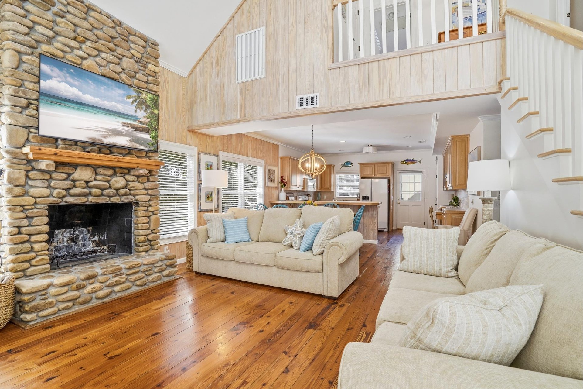 Step in from the covered porch to hardwood floors, a fullheight stone fireplace, and lofted ceilings that open toward the kitchen and dining areas.