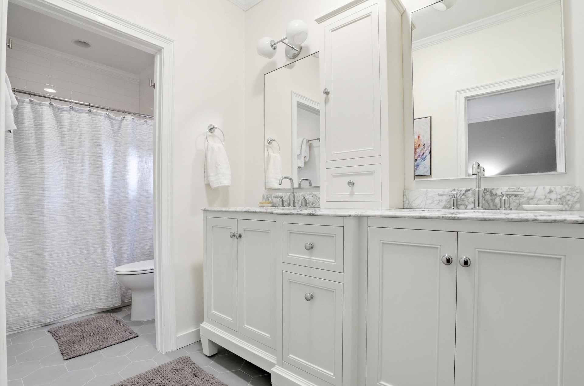 Ensuite bathroom for the main floor king primary suite with double vanity, granite counter, and a tubshower area nearby.